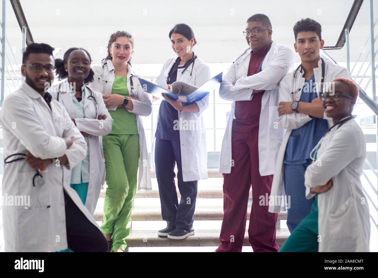 Les étudiants en médecine, médecins, race mixte. Une équipe de jeunes gens en blouse blanche posant dans le couloir de l'hôpital Banque D'Images