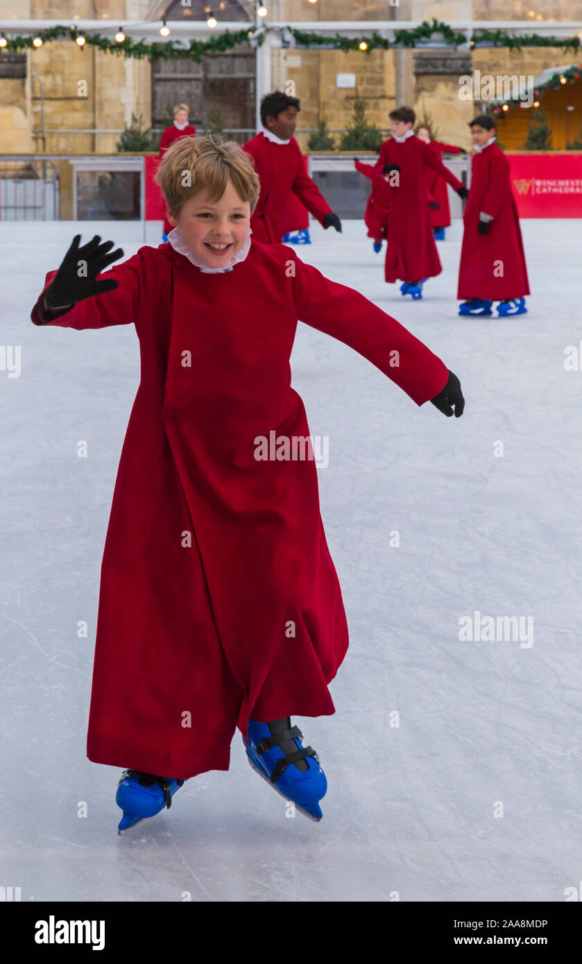 Winchester, Hampshire, Royaume-Uni. 20 novembre 2019. Les choristes le patinage sur la patinoire naturelle de leurs robes rouges emblématiques à la cathédrale de Winchester les fêtes de Noël avec la tradition festive des choristes skating autour de la patinoire d'avance sur son ouverture demain. La patinoire fait partie de la cathédrale de Winchester, marché de Noël, un des plus grands dans le pays. Credit : Carolyn Jenkins/Alamy Live News Banque D'Images