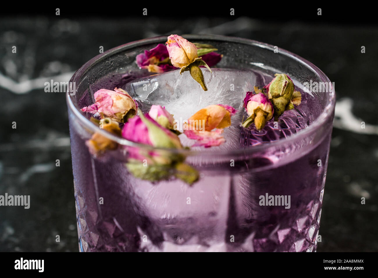 Cocktail Gin Tonic rose avec boutons de rose séchée et de glace en verre tasse. Prêt à boire. Banque D'Images