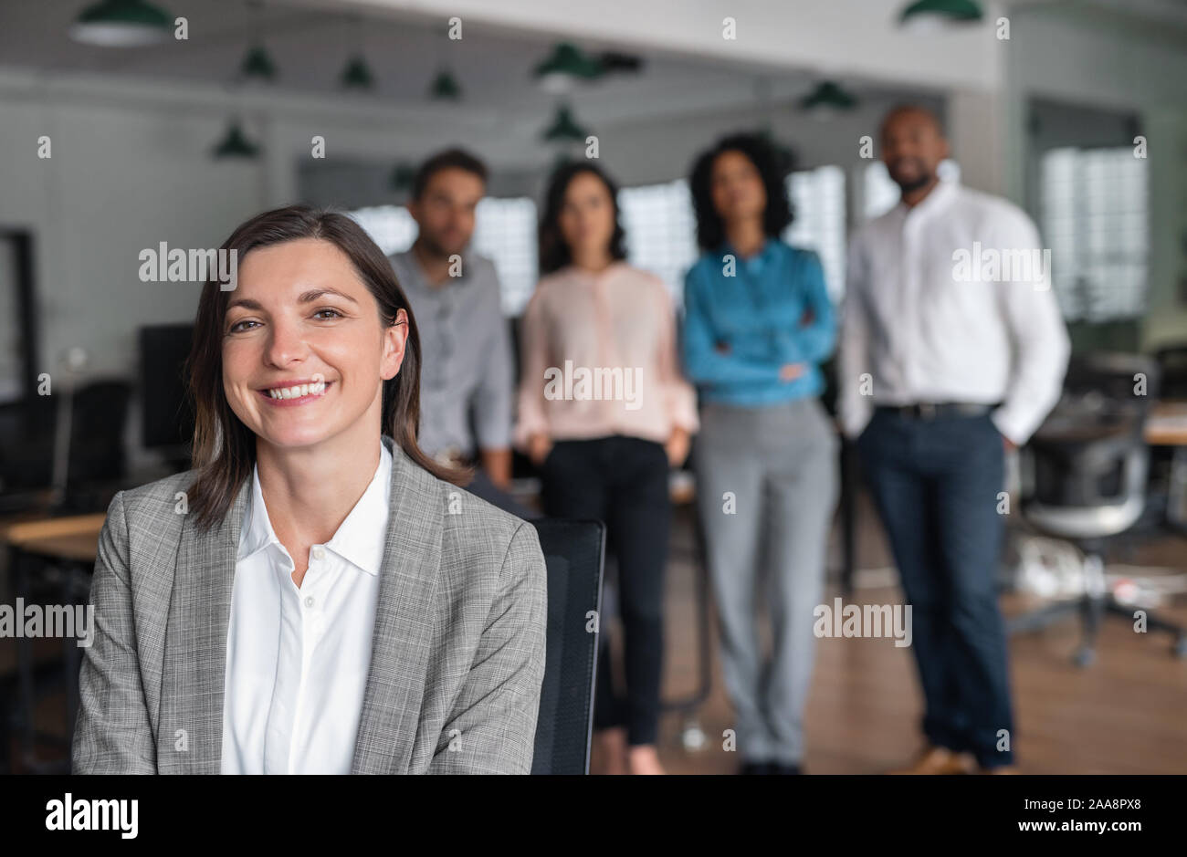 Businesswoman smiling avec des collègues debout dans l'arrière-plan Banque D'Images