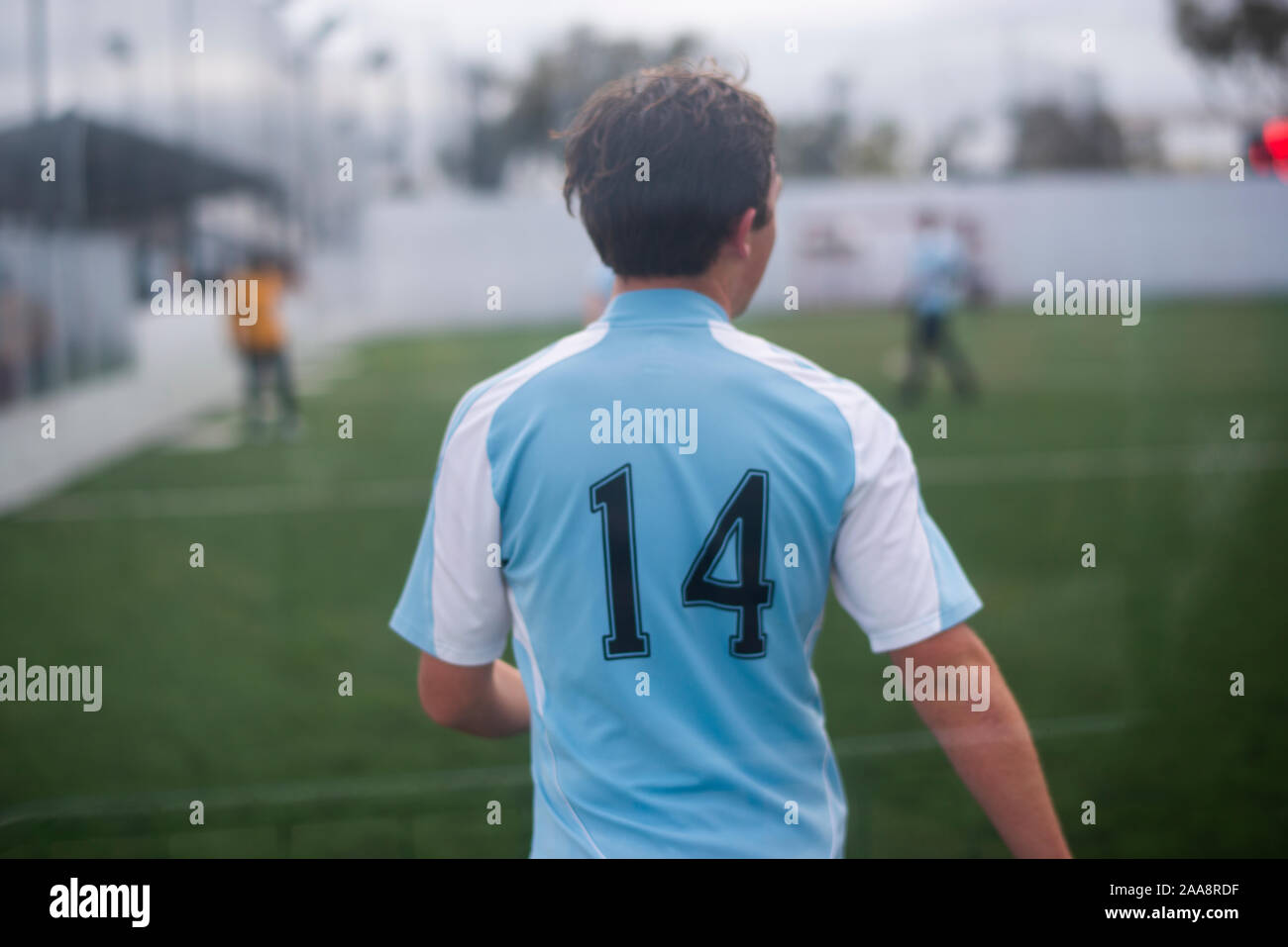 Teenage boy playing soccer intérieur jersey bleu portant le numéro 14 Banque D'Images