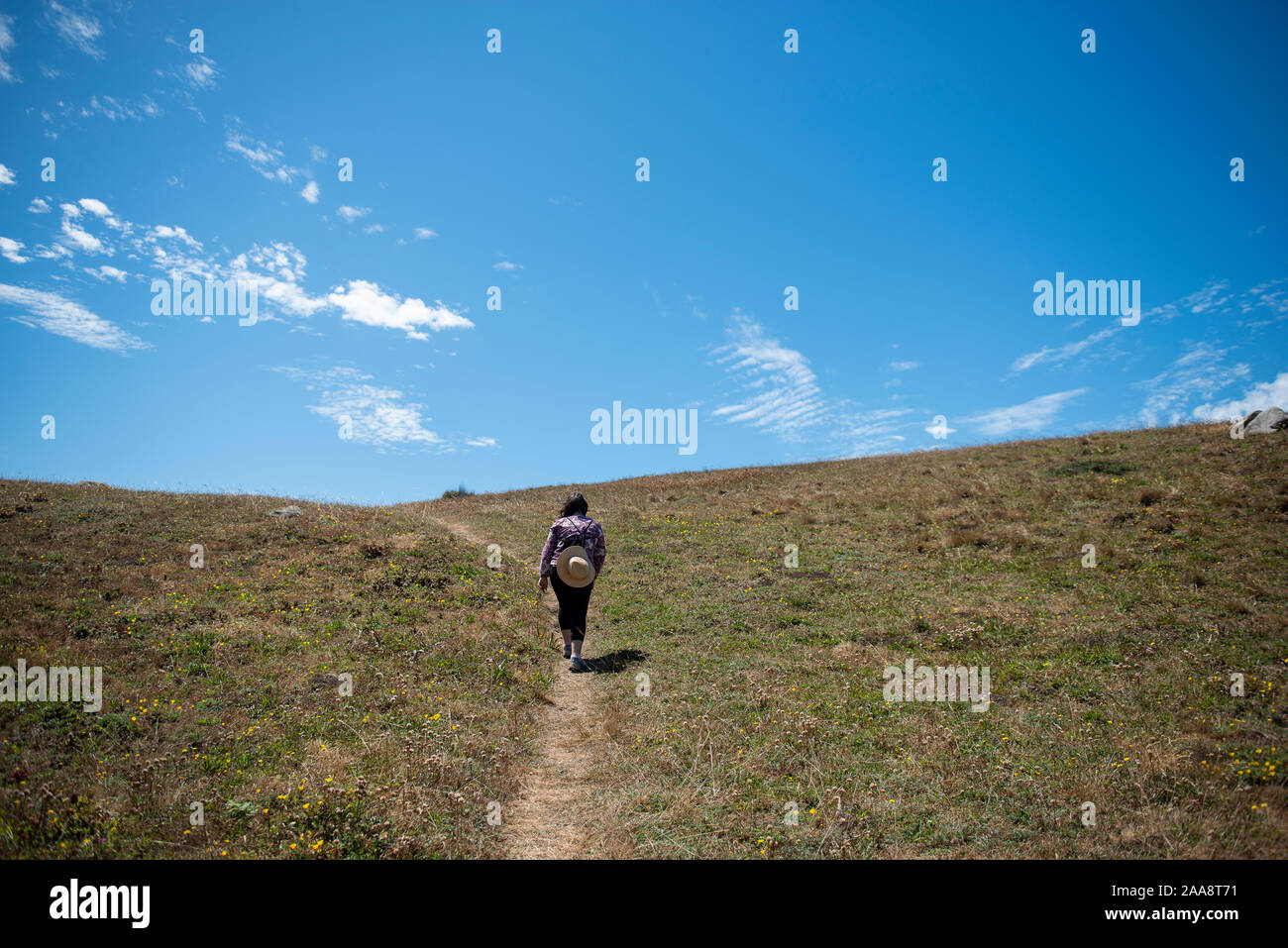 Femme marche jusqu'à ciel bleu sur un chemin à flanc usé naturellement Banque D'Images