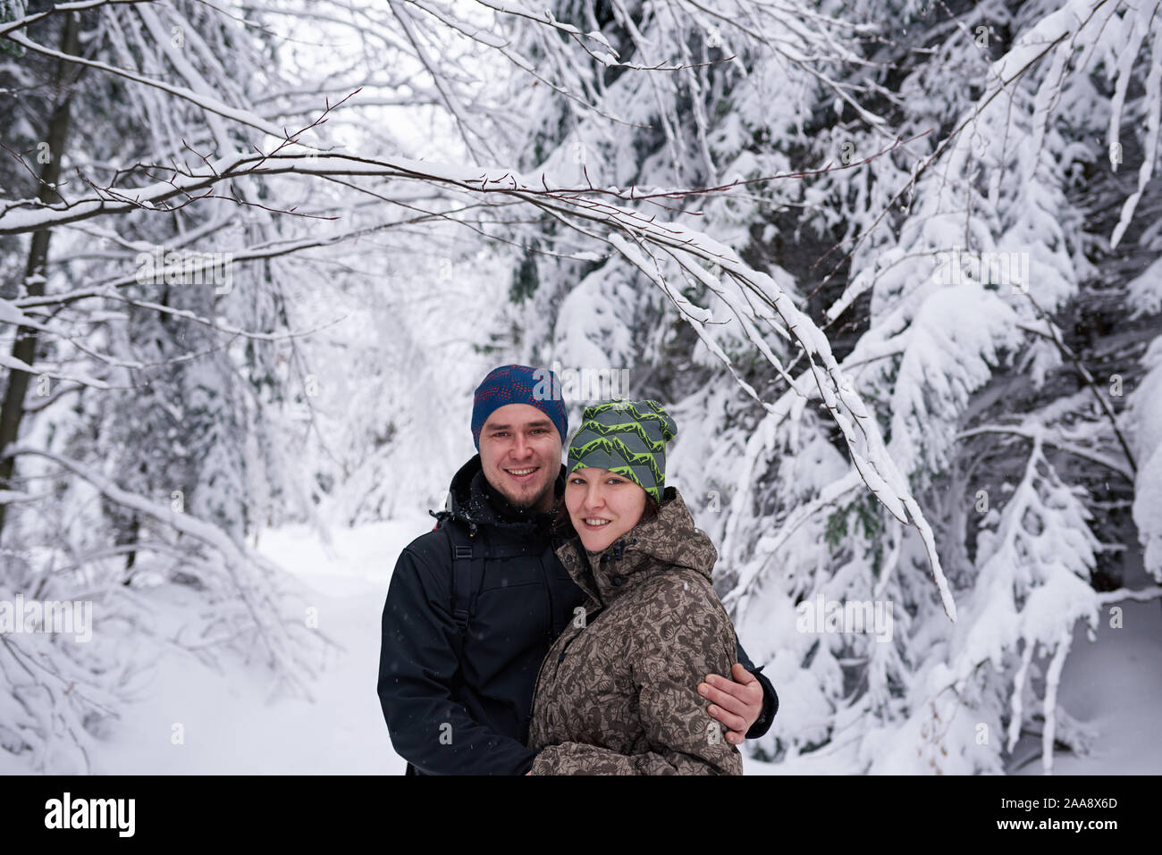 Smiling couple en randonnée ensemble dans une forêt couverte de neige Banque D'Images