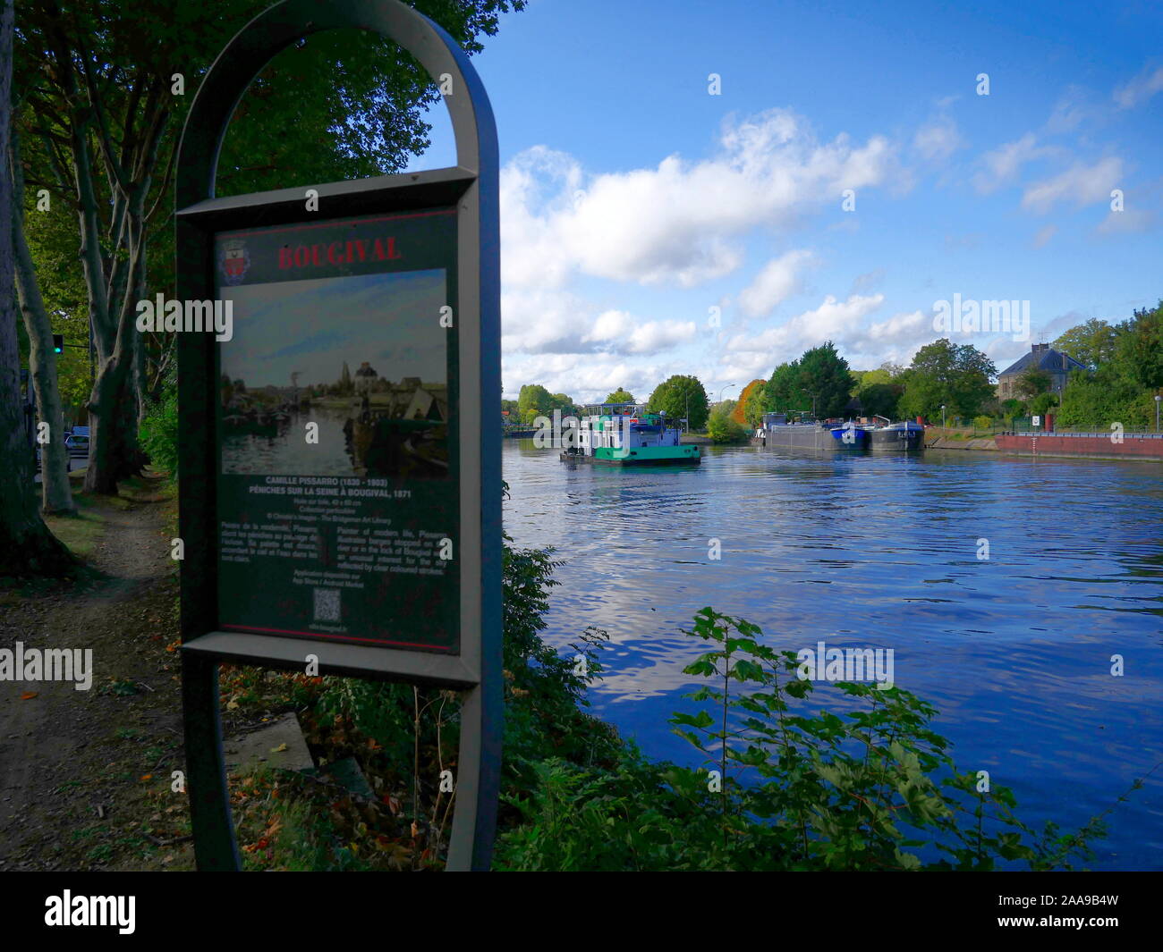 AJAXNETPHOTO. 2019. BOUGIVAL, FRANCE. - Peinture de PISSARRO - PANNEAU D'INFORMATION POUR LA PEINTURE DE L'artiste peintre impressionniste et Camille PISSARRO INTITULÉE "PENICHES SUR LA SEINE UNE BOUGIVAL, 1871', SITUÉ À L'ENDROIT OÙ SUR LES RIVES DE LA SEINE D'OÙ L'ARTISTE A FAIT LA PEINTURE PEUT ÊTRE VU PENICHES FREYCINET AMARRÉS SUR LA RIVE DU FLEUVE PRÈS DE BOUGIVAL LOCK ALORS QU'un remorqueur-pousseur ATTEND D'ENTRER DANS LA SERRURE. photo:JONATHAN EASTLAND/AJAXREF:GX8  20652 192609 Banque D'Images