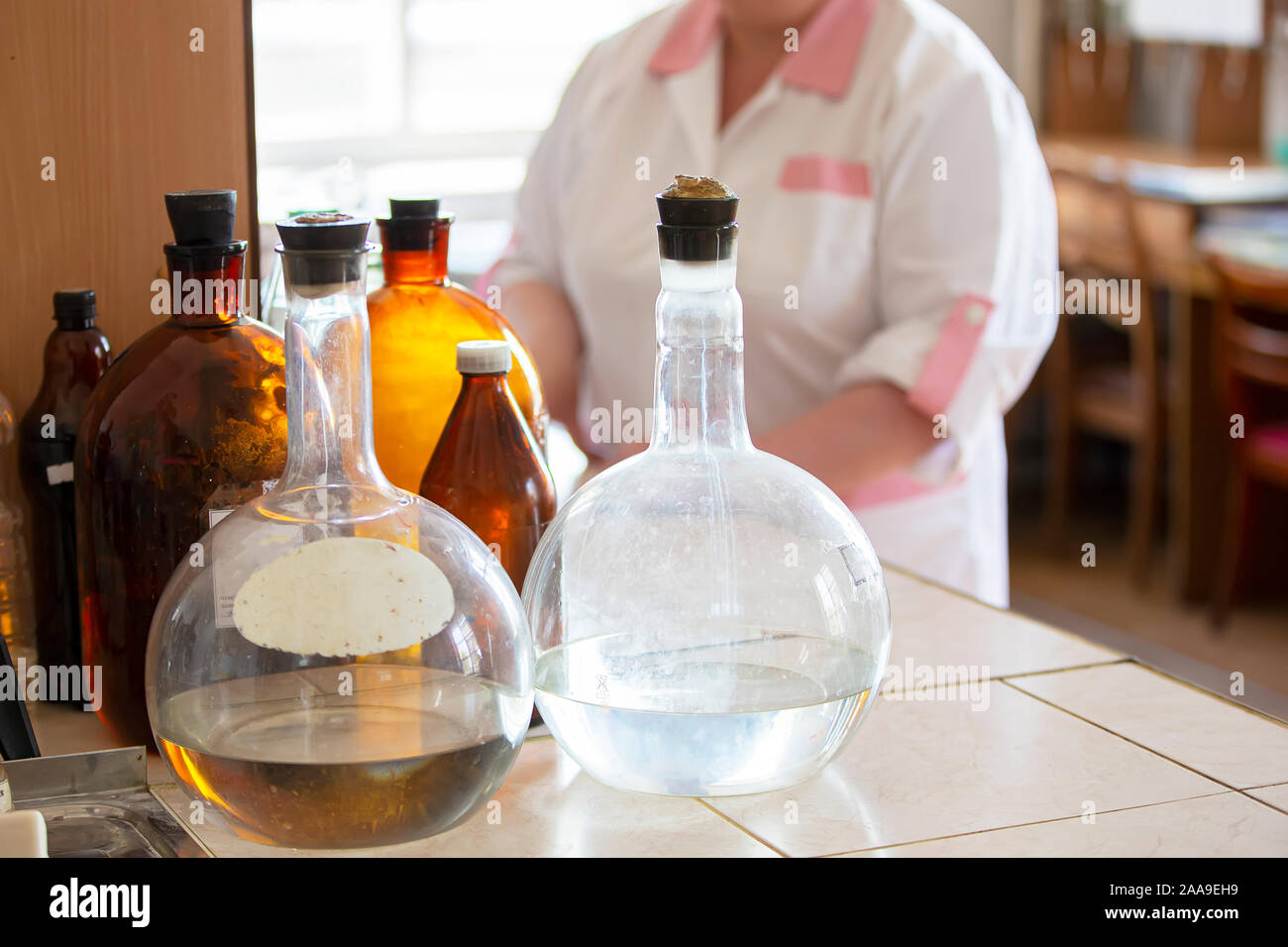 Flacons en verre sur une table de laboratoire. Pharmacie rétro des conteneurs sur l'arrière-plan de l'assistant de laboratoire Banque D'Images