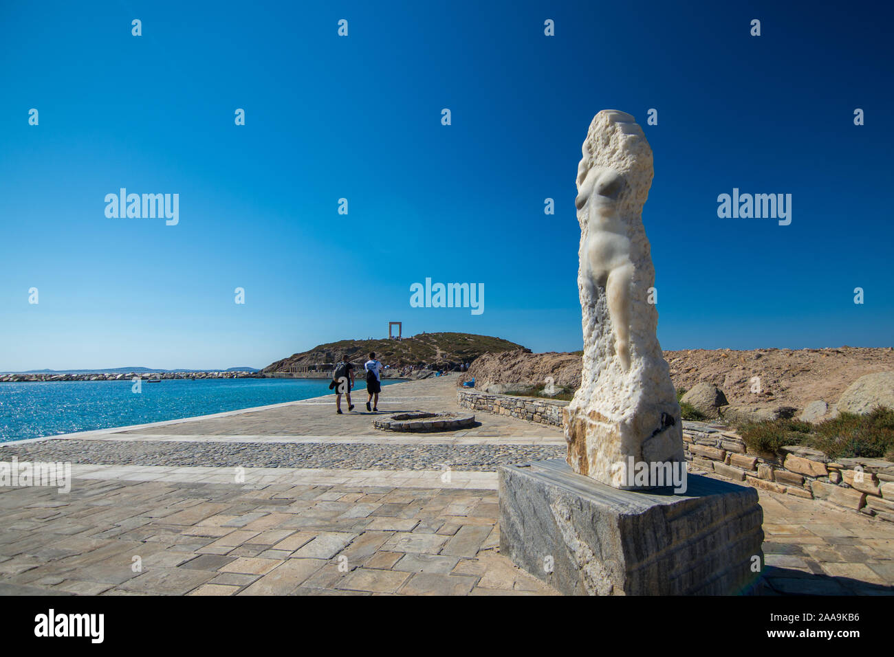 Naxos, Grèce - 12 juillet 2019 : quelques touristes par la statue d'Ariadne sur la promenade menant au temple d'Apollo, Portara ruines sur une journée ensoleillée Banque D'Images