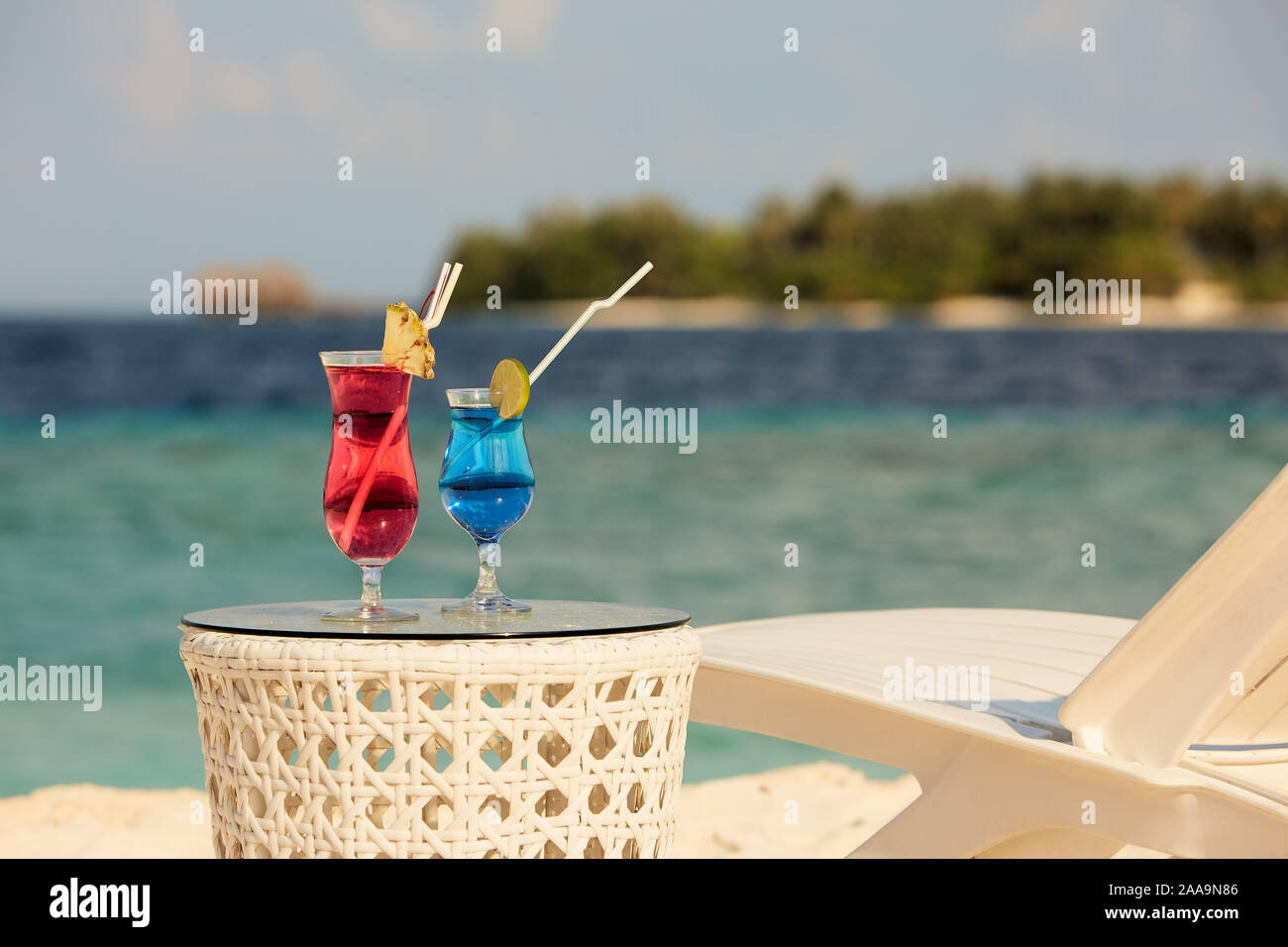 Deux verres avec des cocktails sur la plage près de table banc ou chaise longue avec l'océan bleu et blanc sur fond de sable. Maldives Banque D'Images