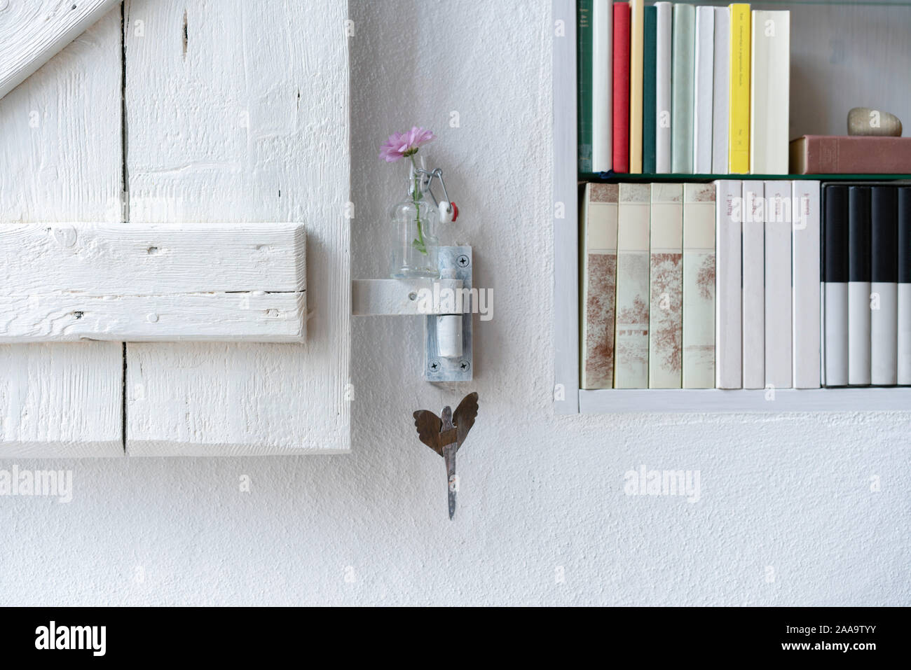 Détail d'une petite bibliothèque avec obturateur, joliment décoré avec un aster rose dans un petit vase en verre Banque D'Images