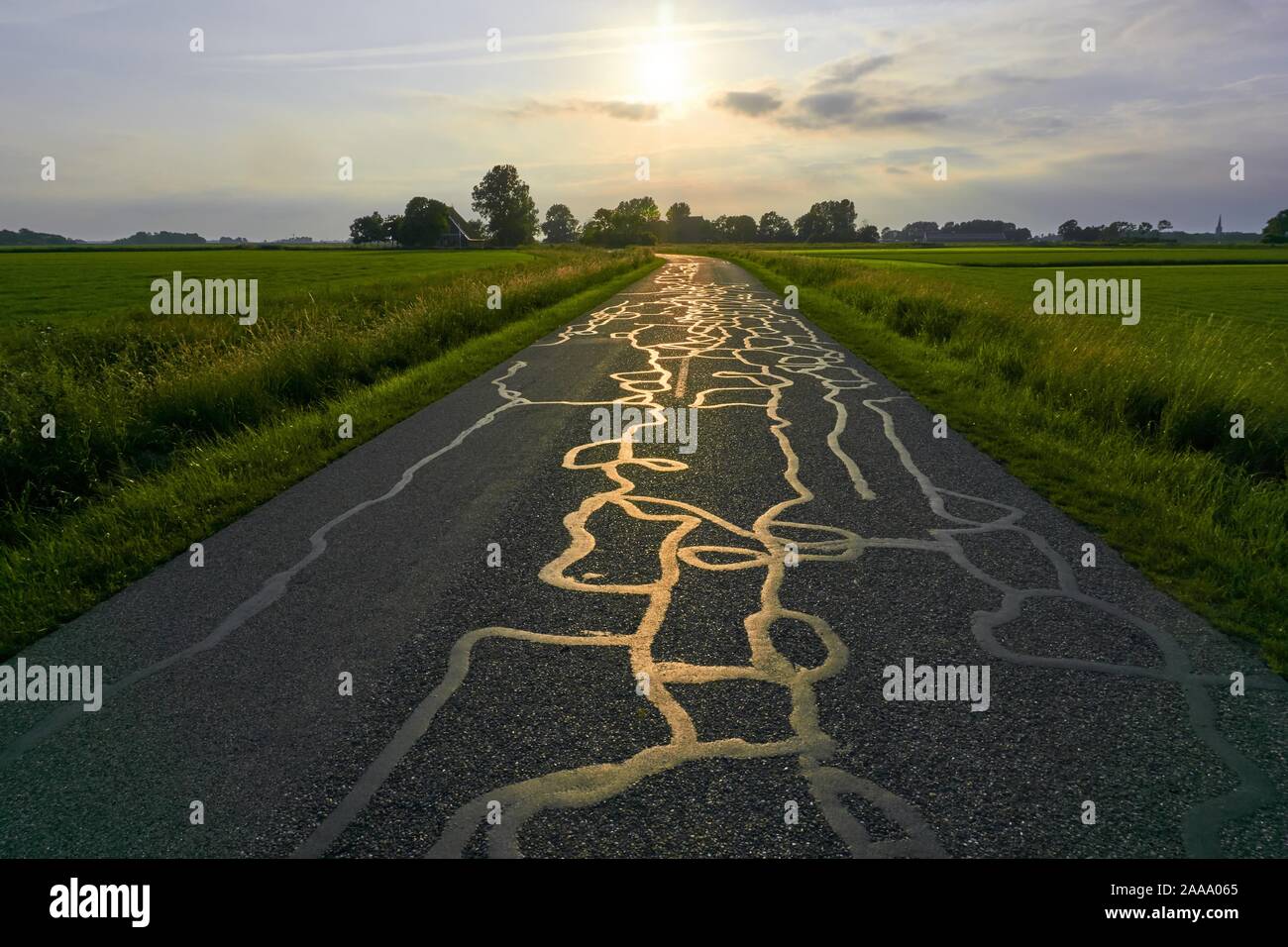 La lumière de coucher de soleil reflétant sur la structure de réparations sur la route goudronnée. Banque D'Images