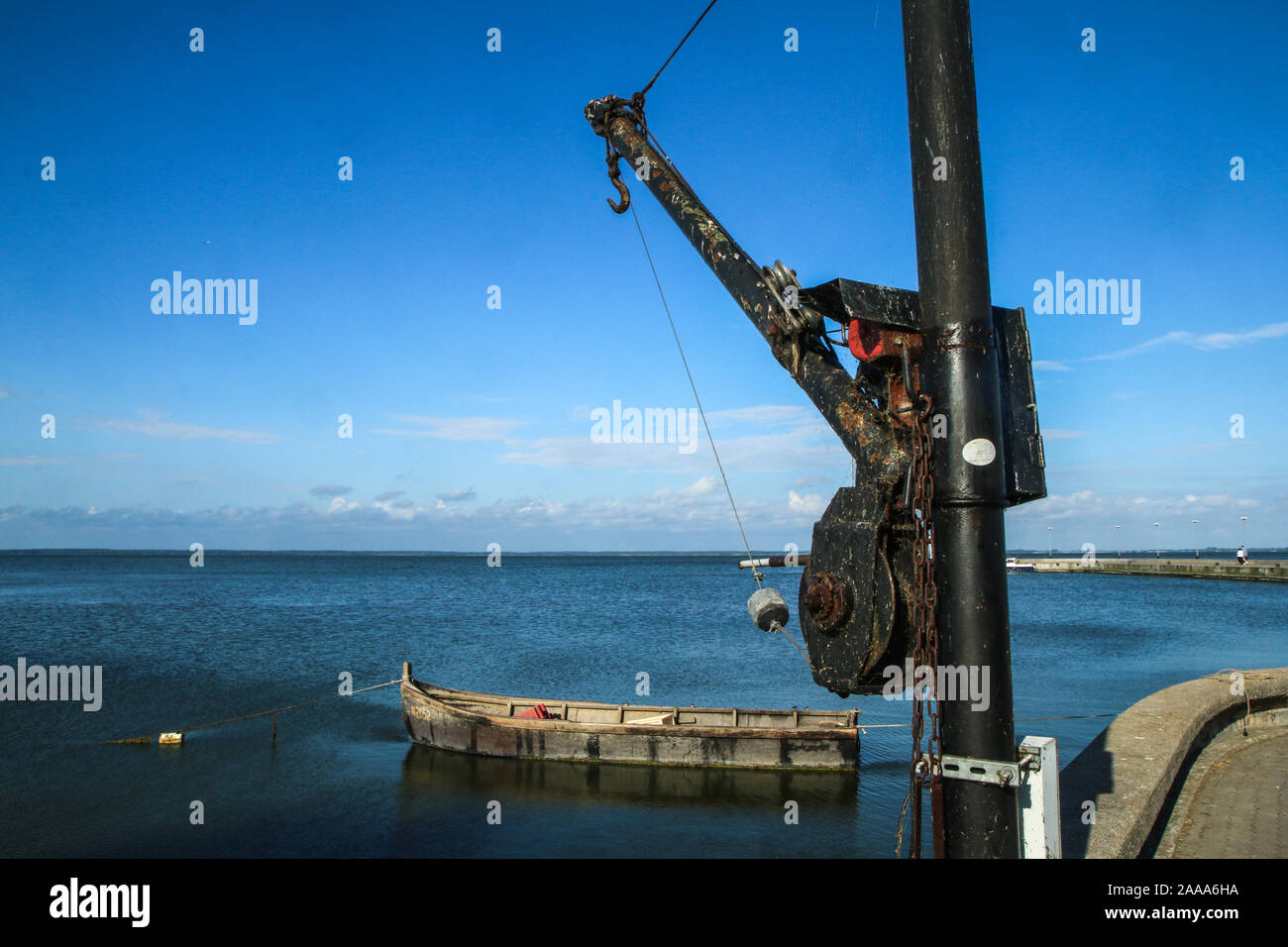 Le calme de la mer en Lituanie dans la ville de Juodkranté. Le bateau de pêcheur est flottante par l'embarcadère et la vieille grue est également visible. Banque D'Images