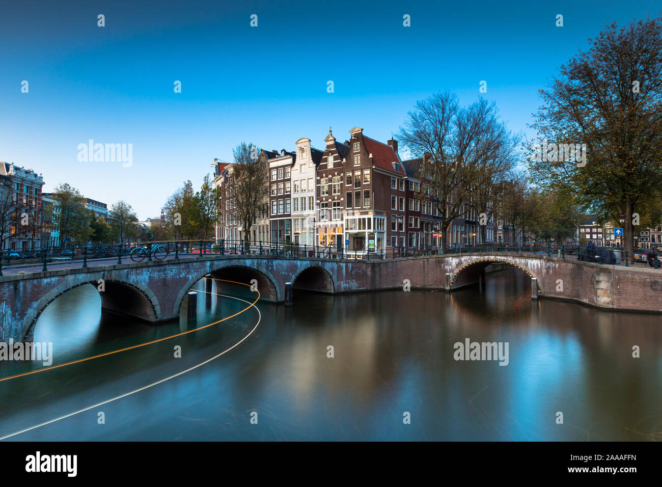 AMSTERDAM, Pays-Bas - 30 octobre 2019 : un pont avec des lumières sur le Keizersgracht Canal pendant l'heure bleue avec des stries de lumières en bateau. Banque D'Images