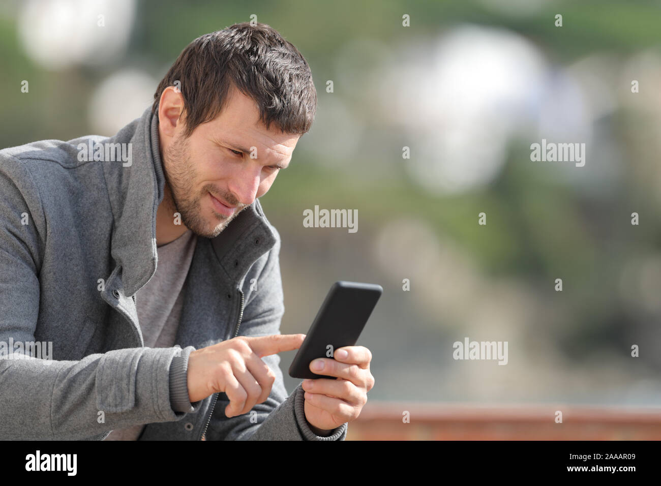 Serious man checking mobile phone app en hiver dans un village rural Banque D'Images