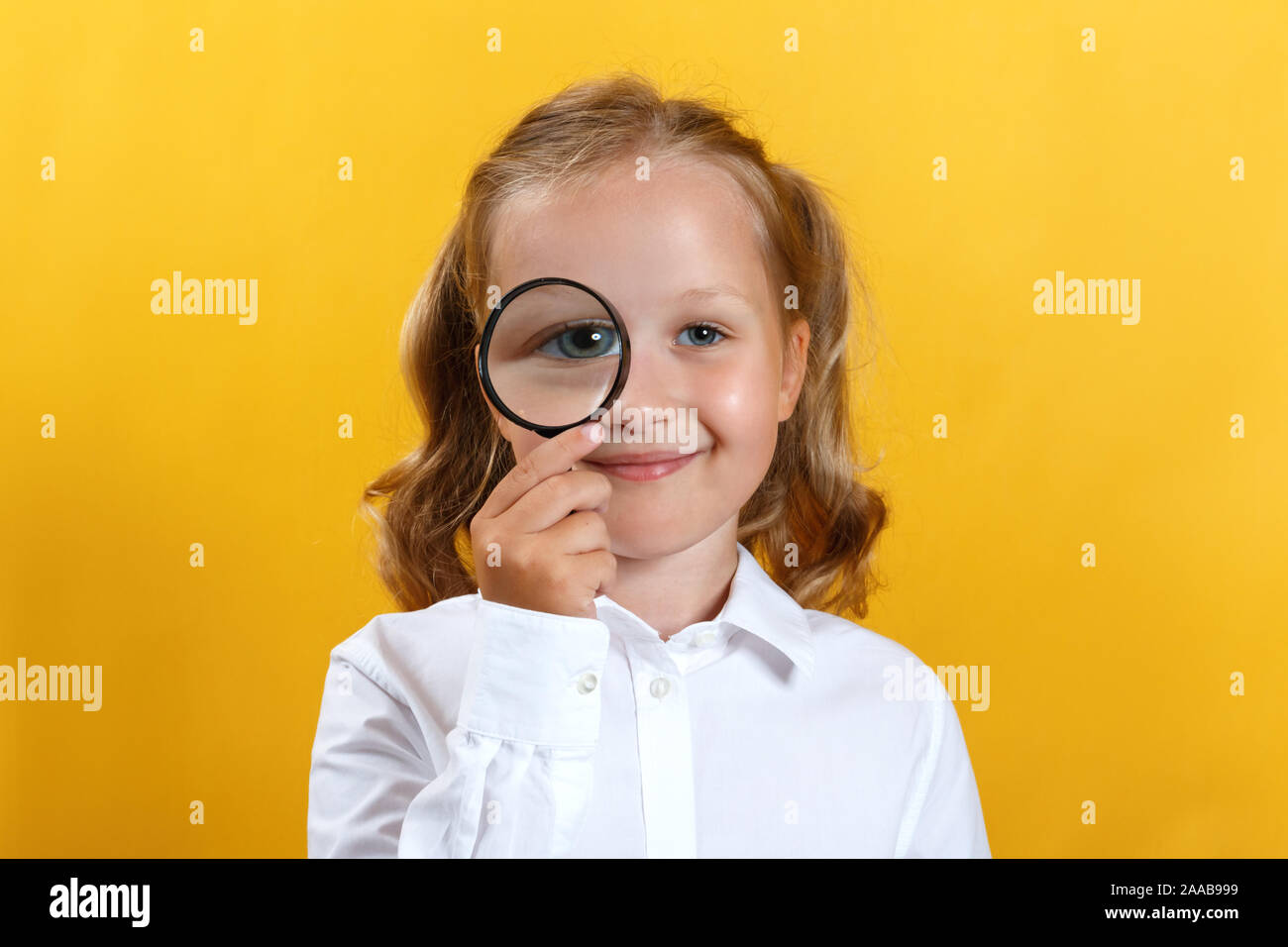 Belle petite fille à travers une loupe. Le concept de l'éducation, l'école, la recherche, la recherche. Banque D'Images