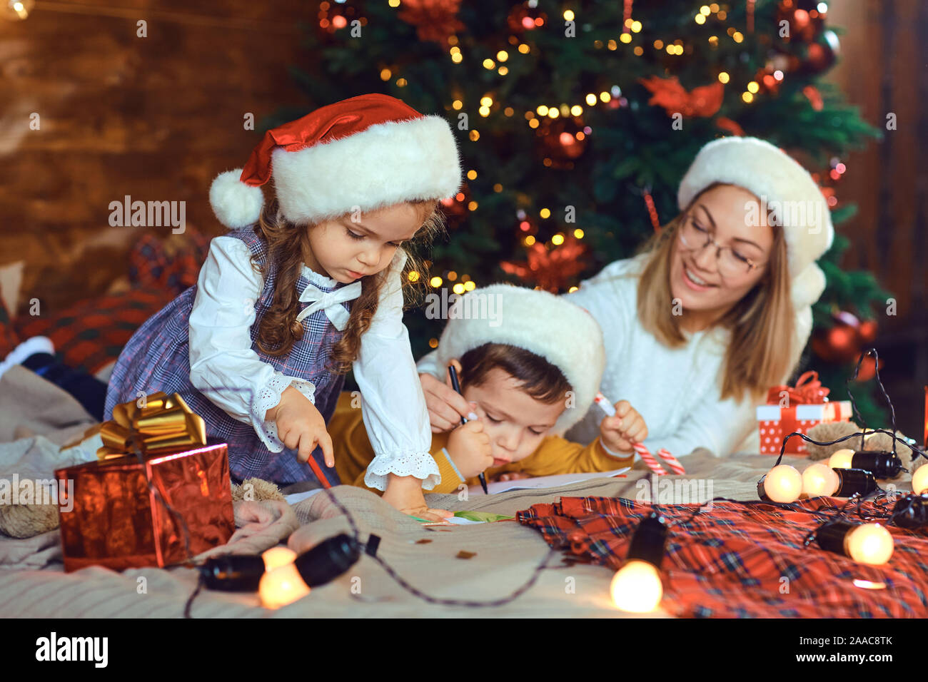 Maman avec enfants attire dans la pièce avec l'arbre de Noël. Banque D'Images