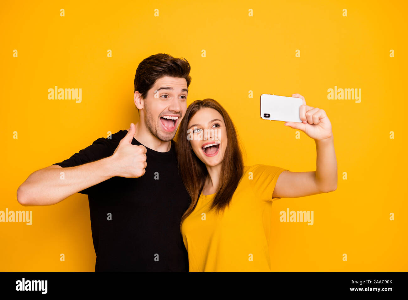 Photo de Happy cute nice charmant couple excité de deux personnes voyageant ensemble en tenant déclenchement selfies émotionnellement showing thumb up symbolisant Banque D'Images
