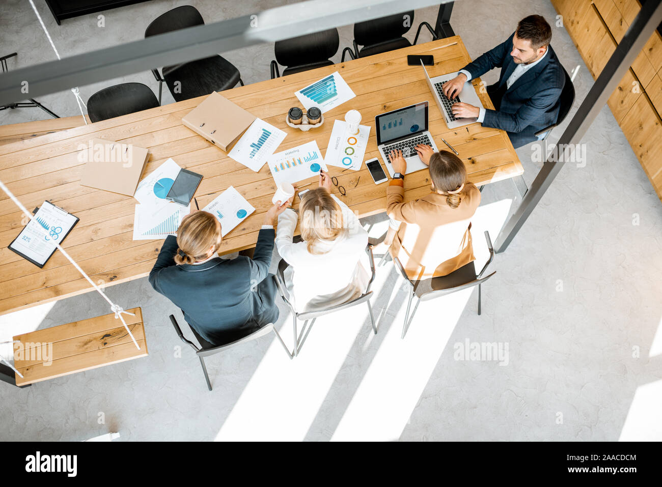 Les gens d'affaires travailler avec les ordinateurs et les statistiques au tableau en bois dans la salle de réunion, voir ci-dessus de la Banque D'Images