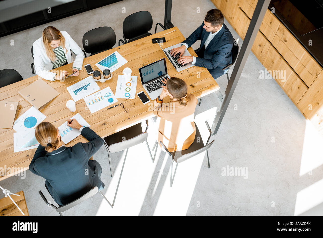 Les gens d'affaires travailler avec les ordinateurs et les statistiques au tableau en bois dans la salle de réunion, voir ci-dessus de la Banque D'Images