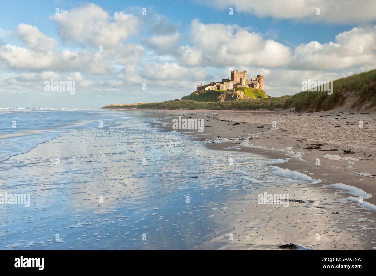 Château de Bamburgh haut perchées sur des rochers escarpés surplombant les dunes côtières, de la plage et de la mer du Nord. Northumberland, Angleterre Banque D'Images