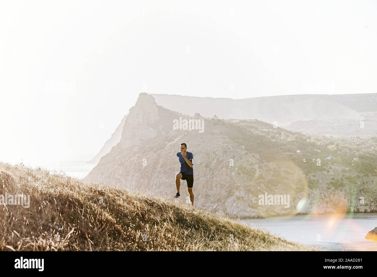Coureur mâle avec des lunettes de soleil dans la montée d'exécution mer baie Banque D'Images