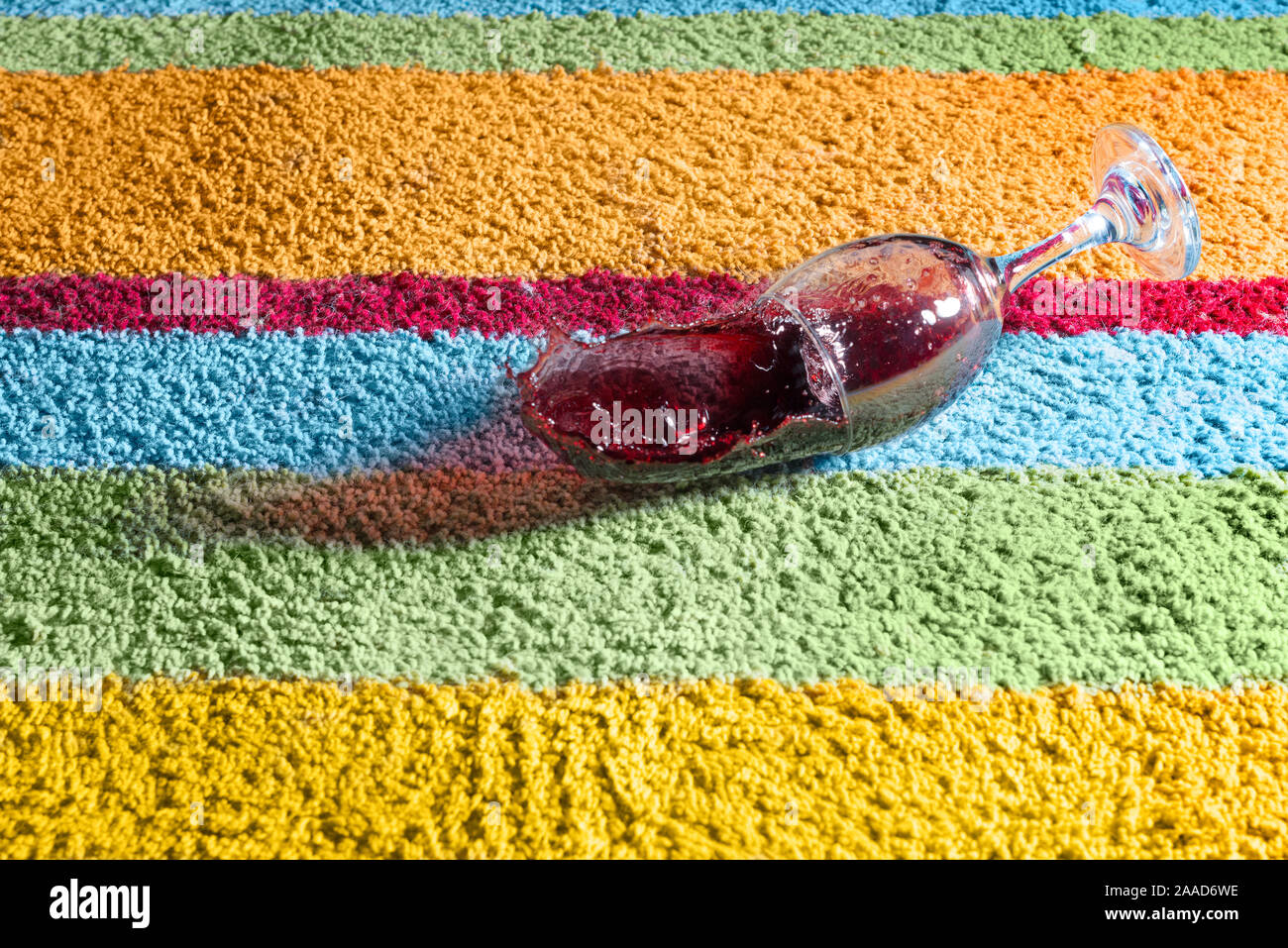 Verre de vin rouge tomber sur le tapis Banque D'Images