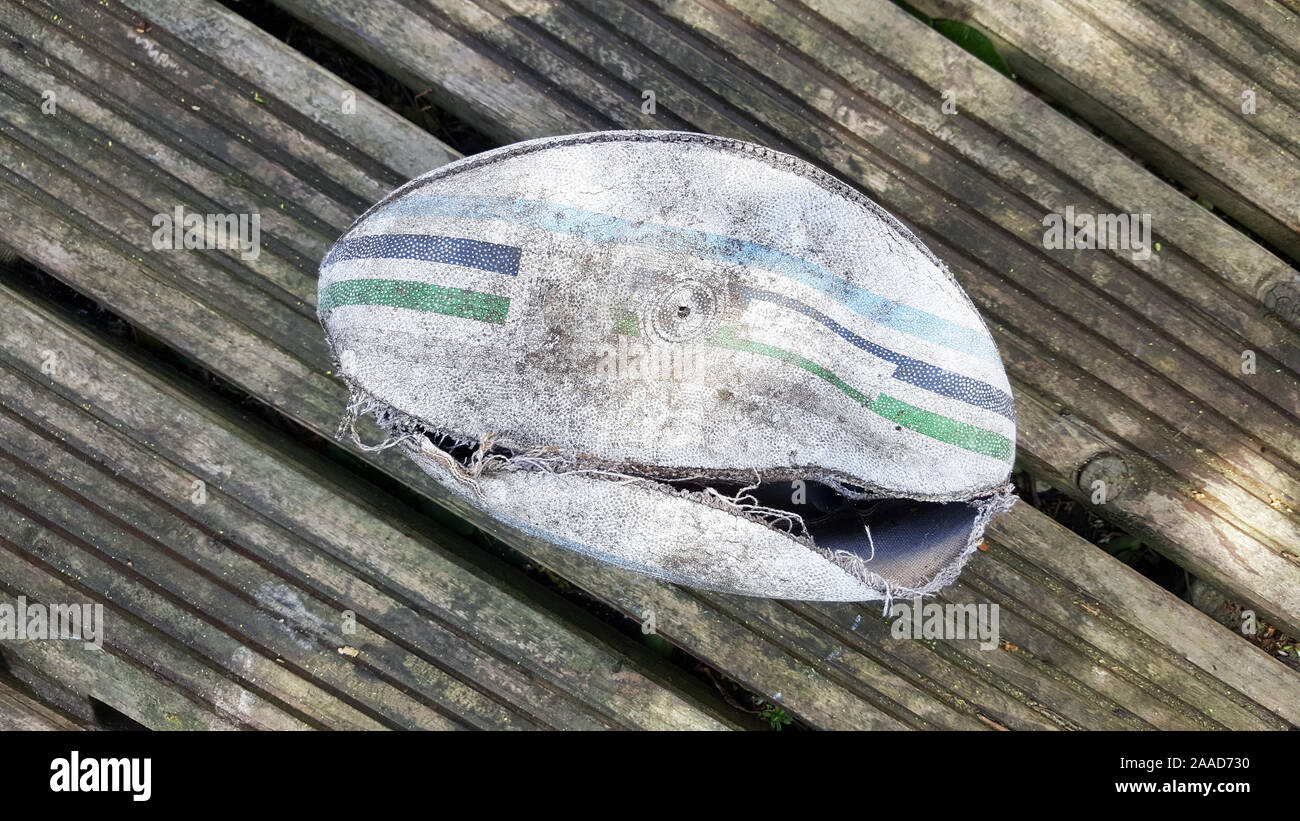 Ballon de rugby en cuir blanc déchiré sur planche en bois historique Banque D'Images