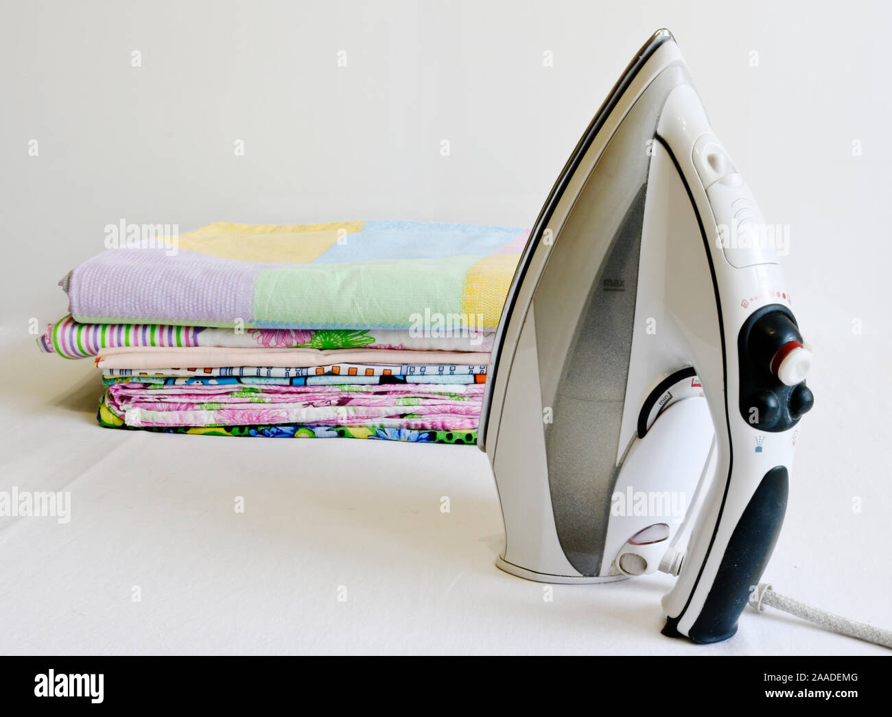 Fer à repasser moderne et pile de linge repassé. Les tâches ménagères. Banque D'Images