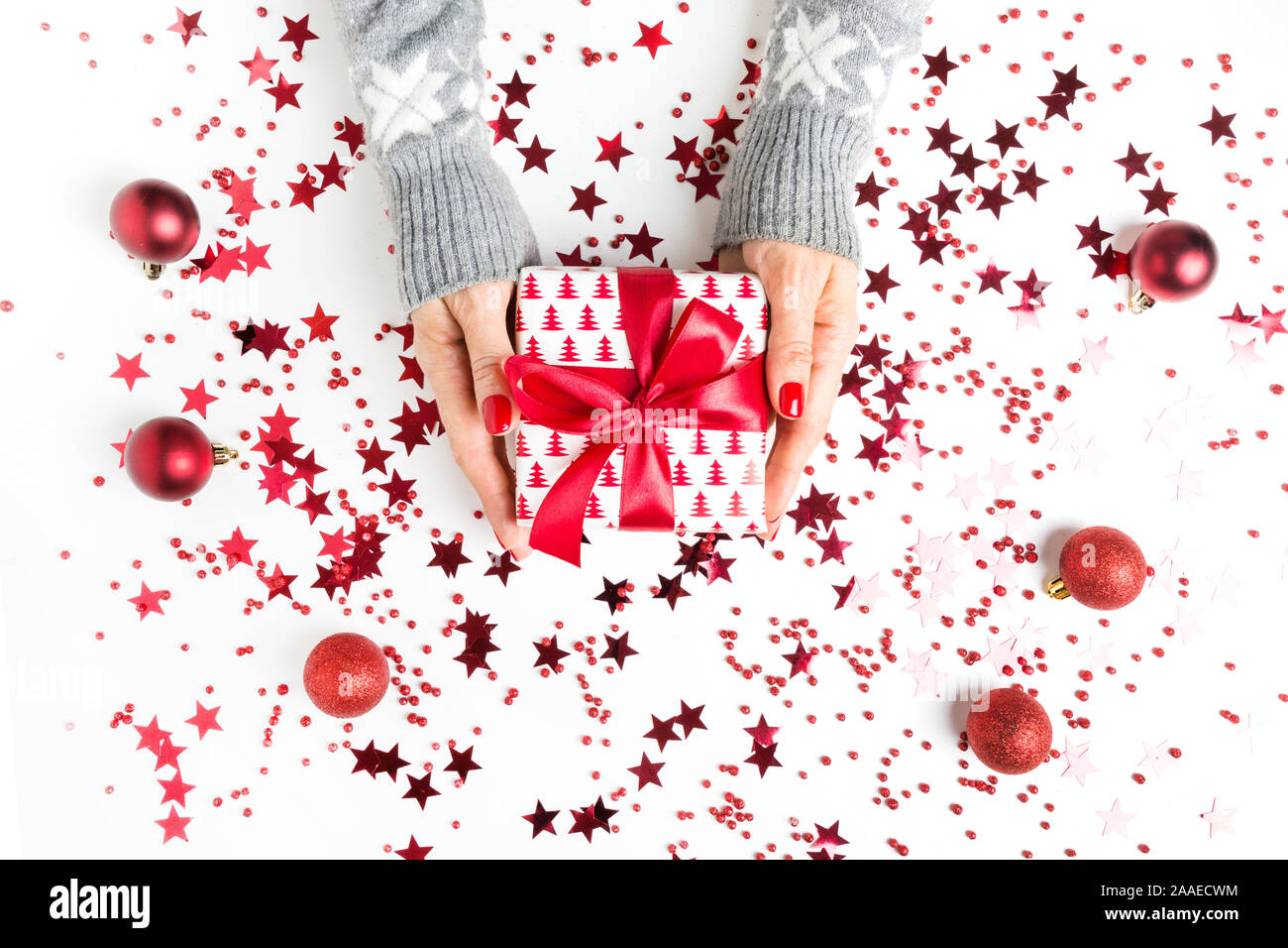 Vacances de Noël en cadeau femme les mains avec décor rouge sur fond blanc. Boxing day. Carte de vœux. Bonne Année. L'espace pour texte, mise à plat. Modèl Banque D'Images
