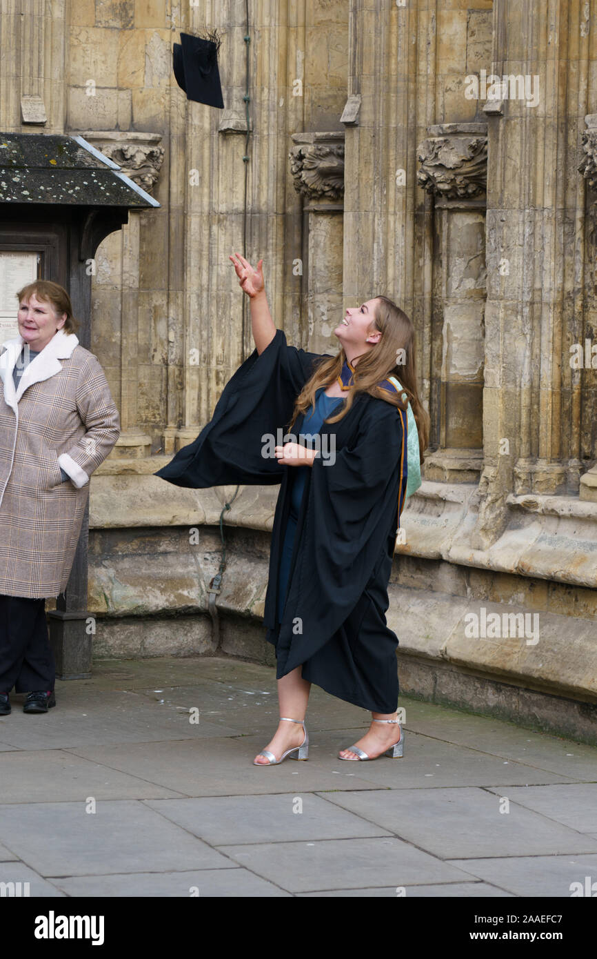 Une étudiante de l'Université York St John jette son chapeau de Mortarboard dans les airs pour célébrer sa remise des diplômes, York Minster, North Yorkshire, Royaume-Uni. Banque D'Images