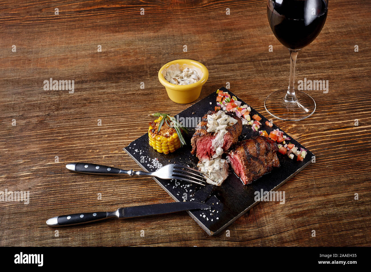 Steak barbecue avec un verre de vin rouge en gros plan sur tableau noir sur fond de bois Banque D'Images
