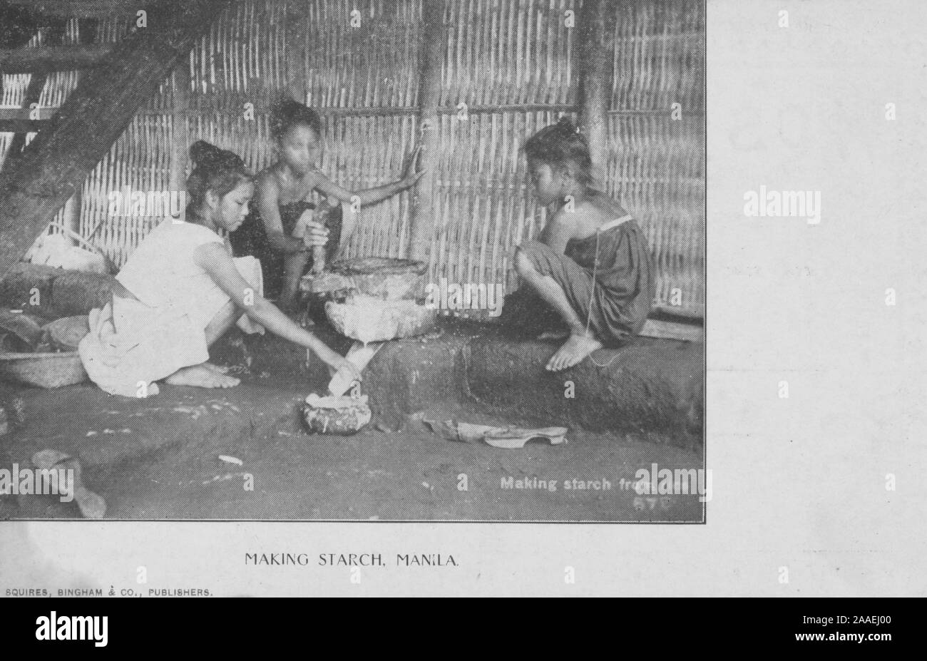 Carte postale monochrome d'un groupe de jeunes filles accroupis dans une cabane autour d'un pot, faire de l'amidon de riz, les Philippines, publié par Squires, Bingham et Co, 1905. À partir de la Bibliothèque publique de New York. () Banque D'Images
