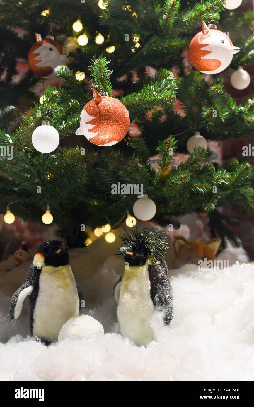 Arrière-plan de fête verticale, Nouvel An fête composition, pingouins dans la neige et un arbre de Noël avec une guirlande et décorations Banque D'Images