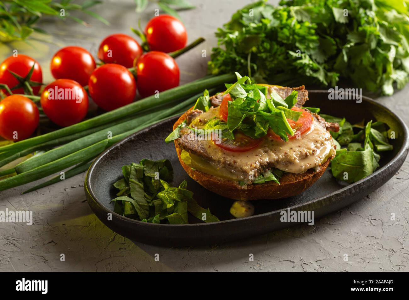 La bruschetta avec un rôti de bœuf - Filet de veau cuit salé avec le concombre, la tomate, les épinards et la sauce à la moutarde sur une poêlée de petit pain dans une plaque noire sur un g Banque D'Images