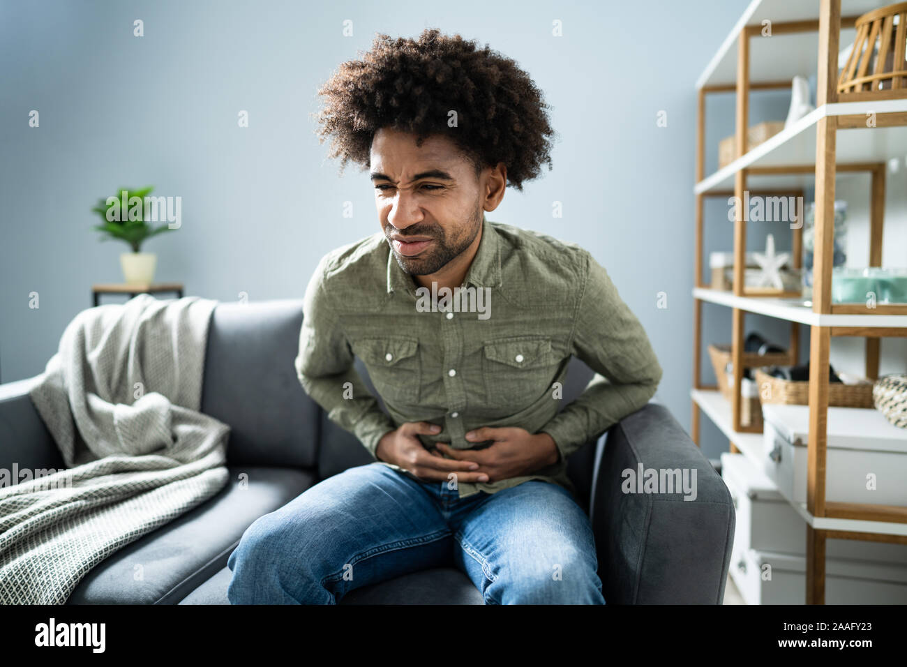 Portrait de l'homme avec l'estomac assis sur table à la maison Banque D'Images