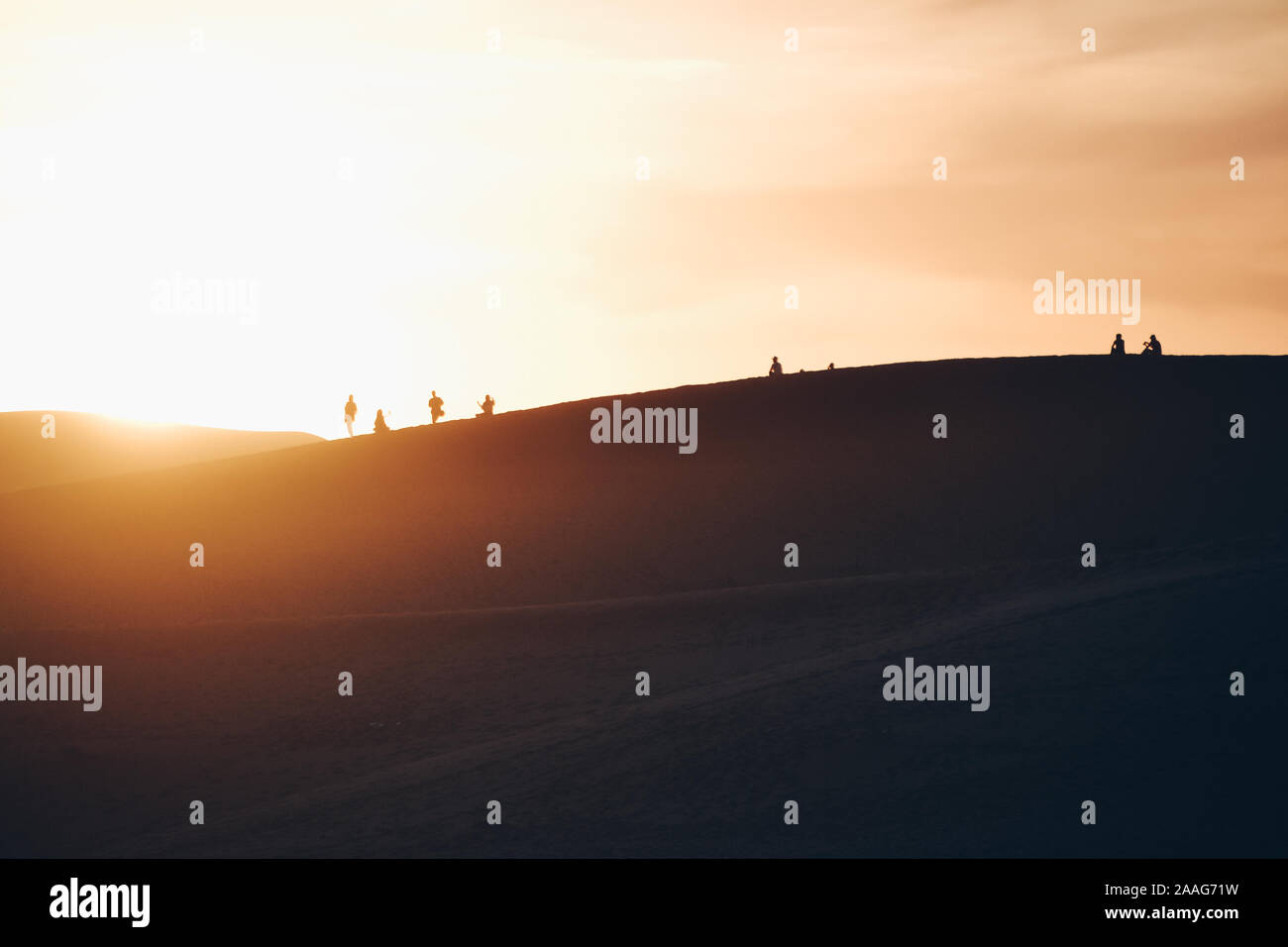 Silhouette de plusieurs personnes regardant le coucher du soleil dans le désert Banque D'Images