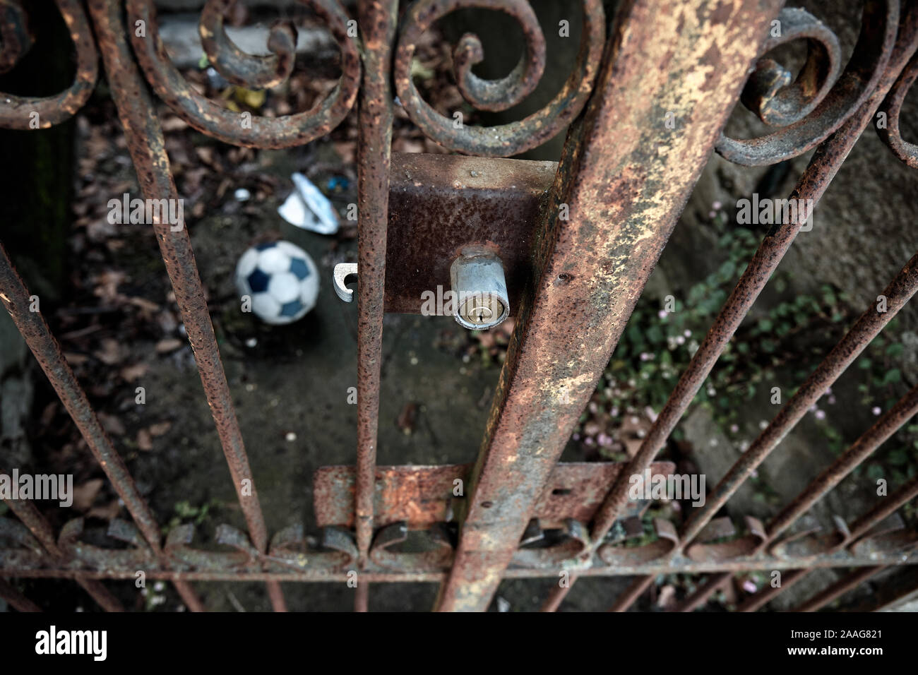 Le ballon de soccer est clôturé, derrière les barreaux d'une grille de fer rouillée. Banque D'Images