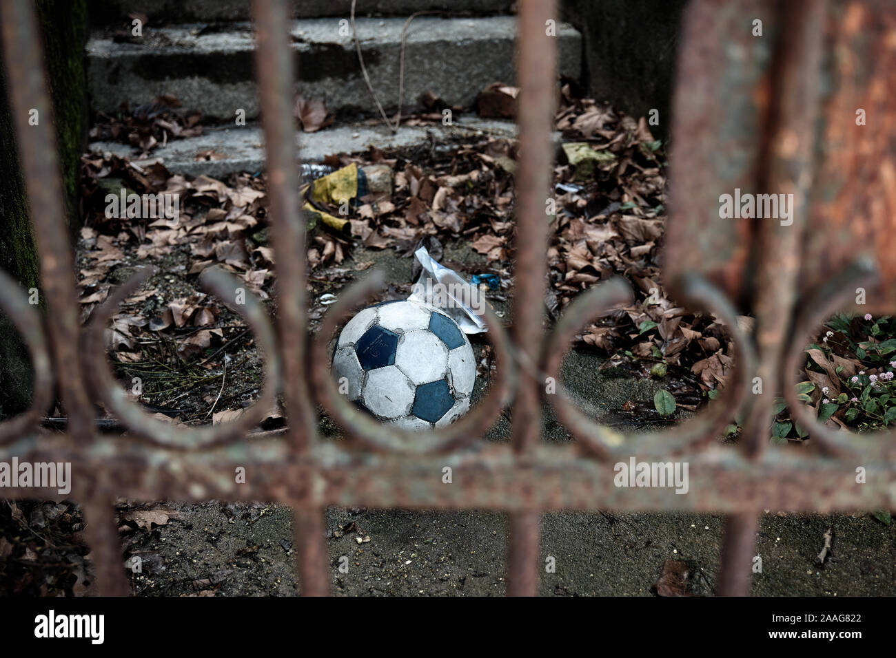 Le ballon de soccer est clôturé, derrière les barreaux d'une grille de fer rouillée. Banque D'Images