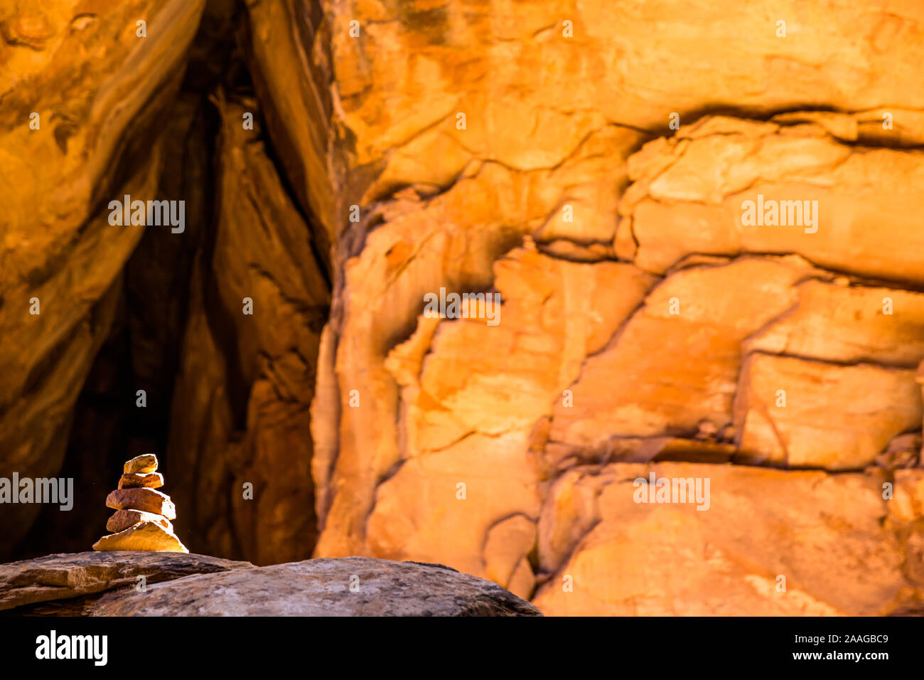 Cairn dans la fente étroite canyon de grès orange lumineux éclairé par bande étroite de la lumière du soleil d'en haut. Banque D'Images