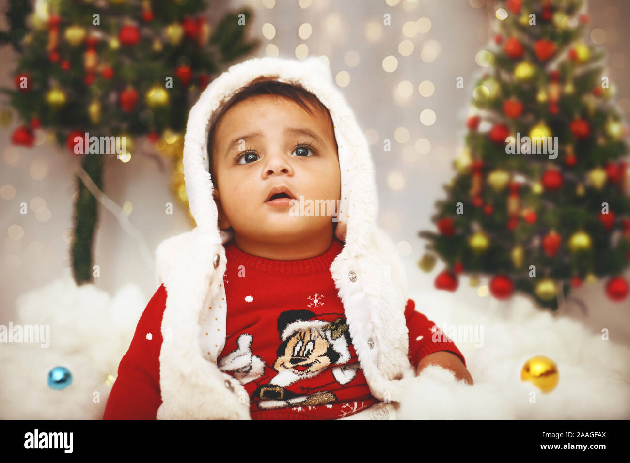 Peu mignon bébé célèbre festival de Noël au sein de l'arrière-plan décoratif à l'occasion. Banque D'Images