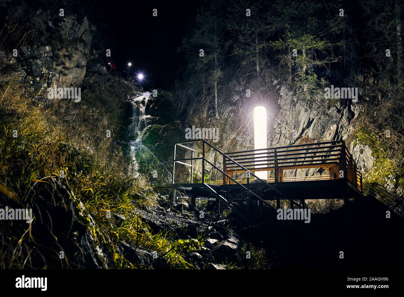 Grande lampe Led allumé à plate-forme en bois pour le camping près de cascade dans les montagnes sous le ciel de nuit avec des étoiles Banque D'Images