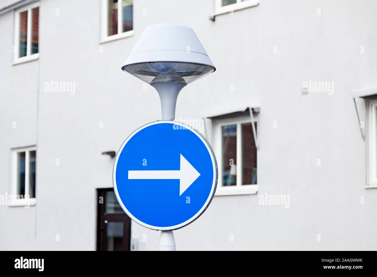 Un lampadaire avec un panneau de circulation rond avec fond bleu et une ...