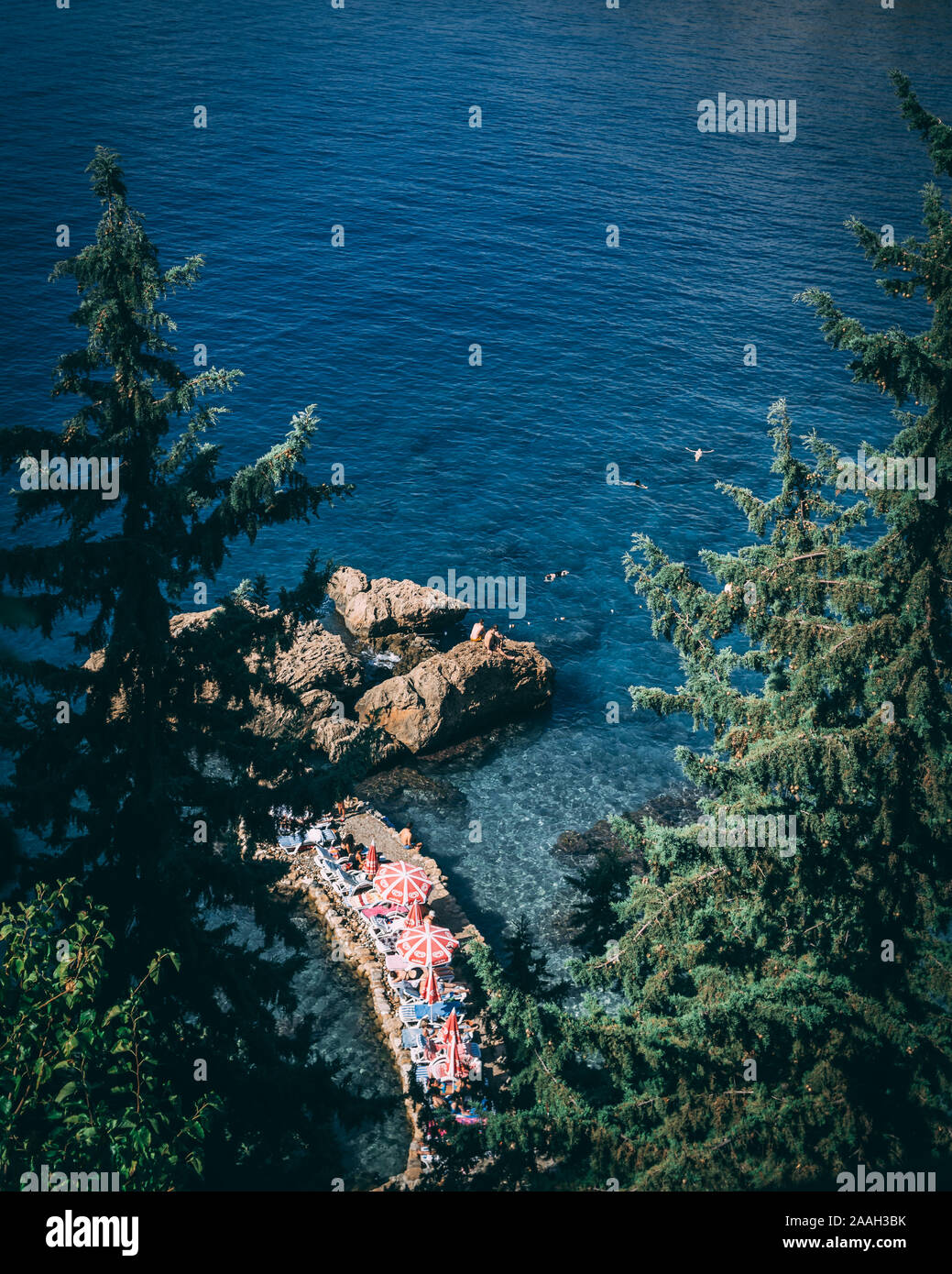 Antalya, Turquie - 6 octobre 2019 : les gens au soleil au bord de la mer sur les rochers. À partir de l'image ci-dessus, à travers les arbres. Banque D'Images Antalya, Turquie - 6 octobre 2019 : les gens au soleil au bord de la mer sur les rochers. À partir de l'image ci-dessus, à travers les arbres. Banque D'Images