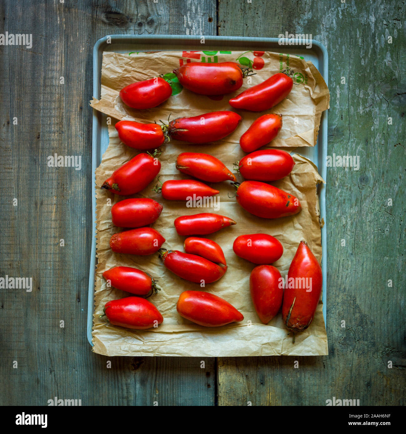 Vue en grand angle des tomates raisins sur un plateau sur la table en bois sous les lumières Banque D'Images