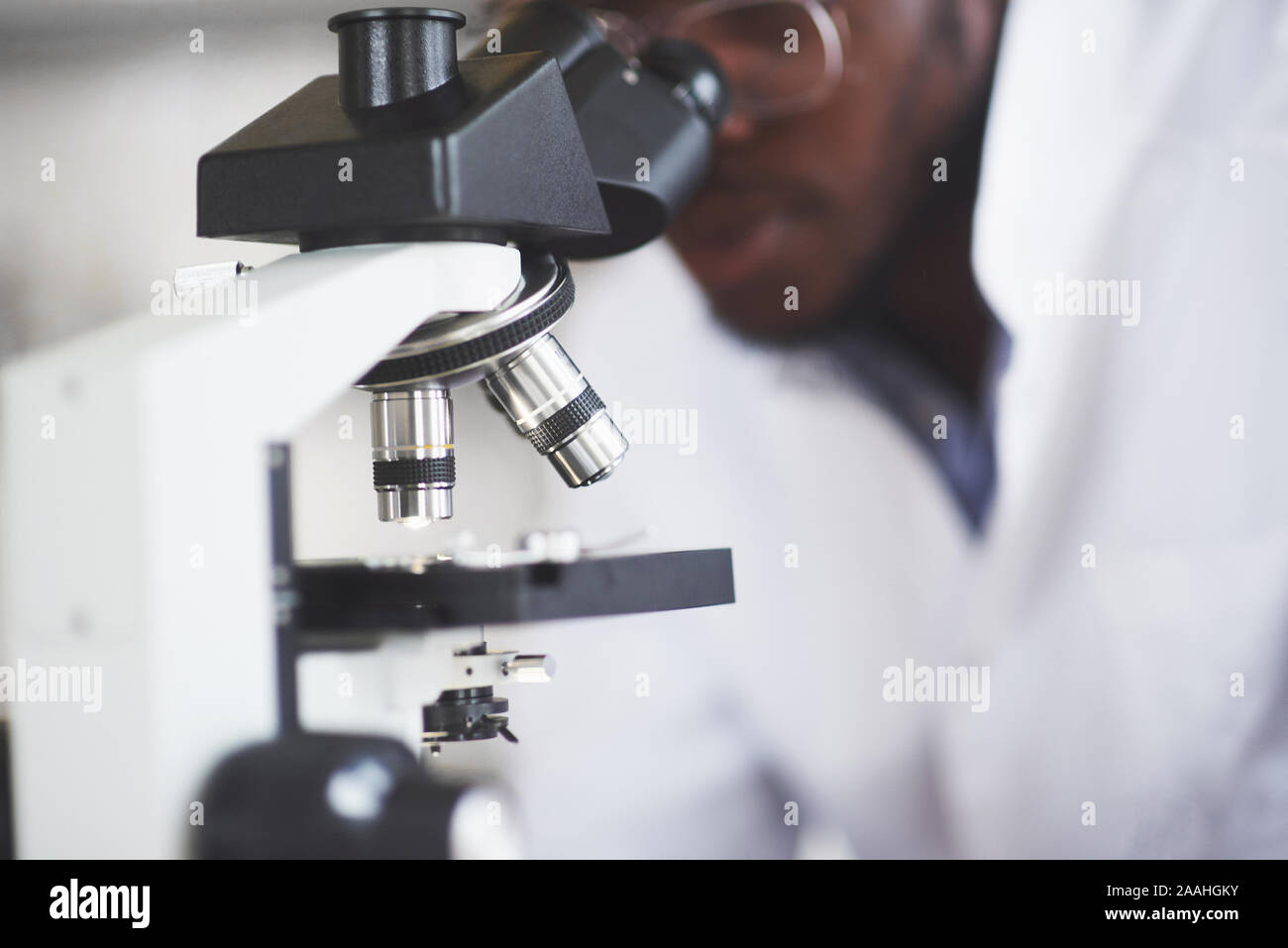 Le scientifique travaille avec un microscope dans un laboratoire effectuant des expériences et des formules. Banque D'Images