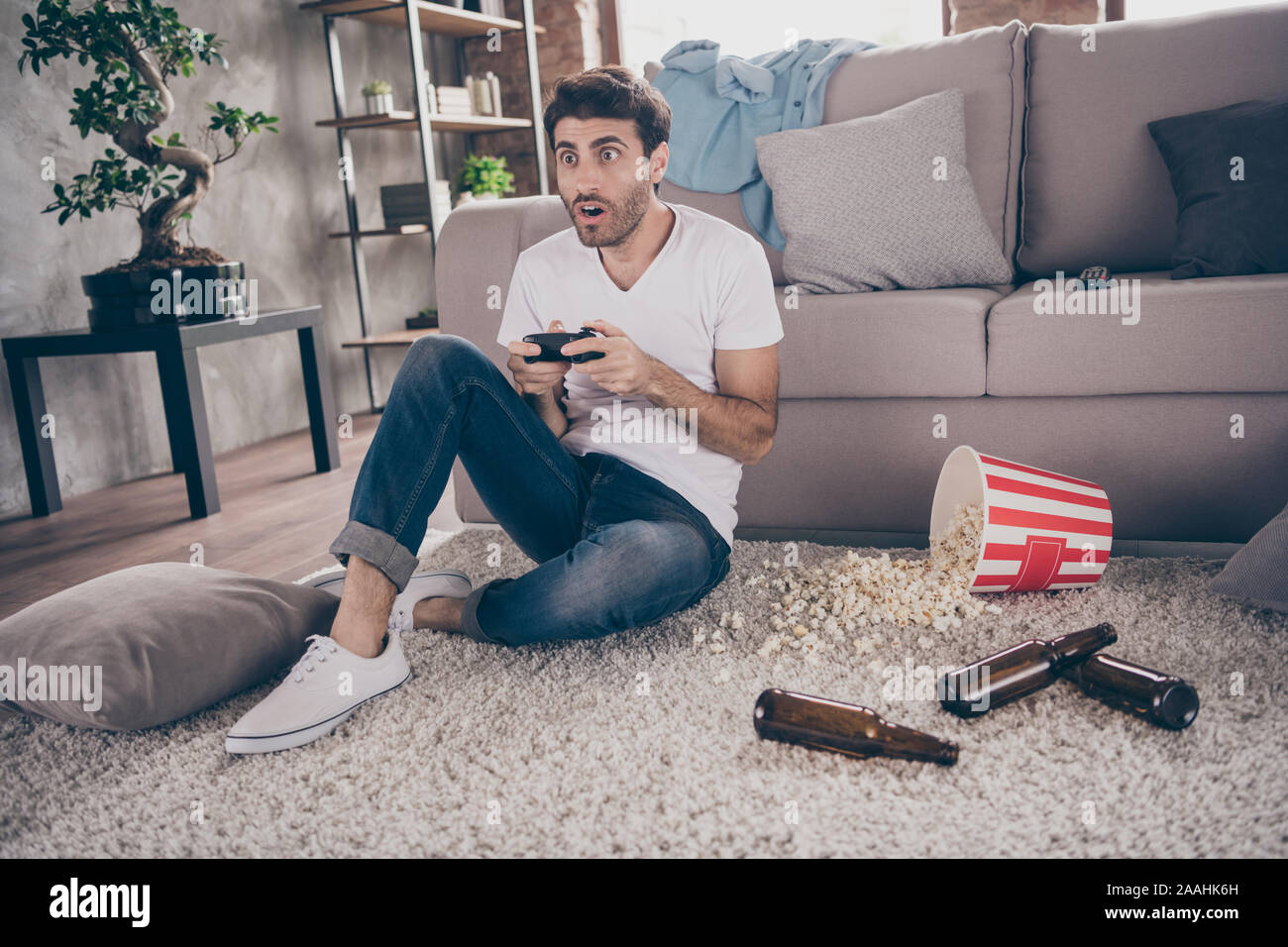 Photo de race mixte arabian guy sitting leaning tapis canapé maintenez joystick jeux vidéos veulent gagner excité les bouteilles de bière vides sur le plancher popcorn Banque D'Images