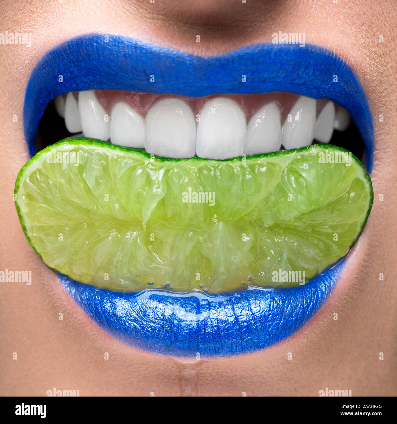 Les lèvres bleues de mordre sur tranche de lime Banque D'Images