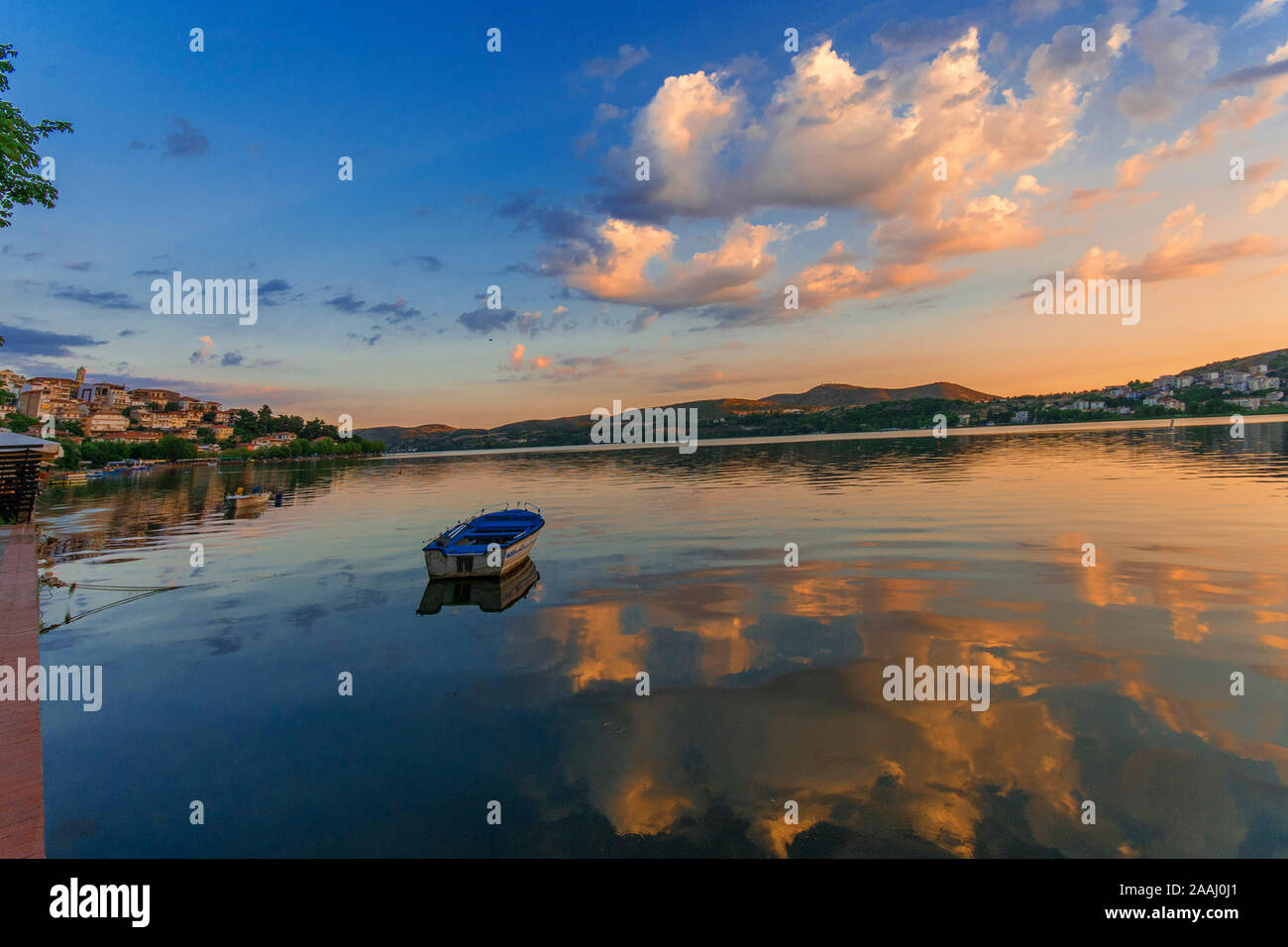 Un bateau flottant paisiblement sur un très calme et silencieux lac au crépuscule à Kastoria, Grèce. Magnifique coucher de soleil couleurs bleu, rose, jaune et orange. Banque D'Images