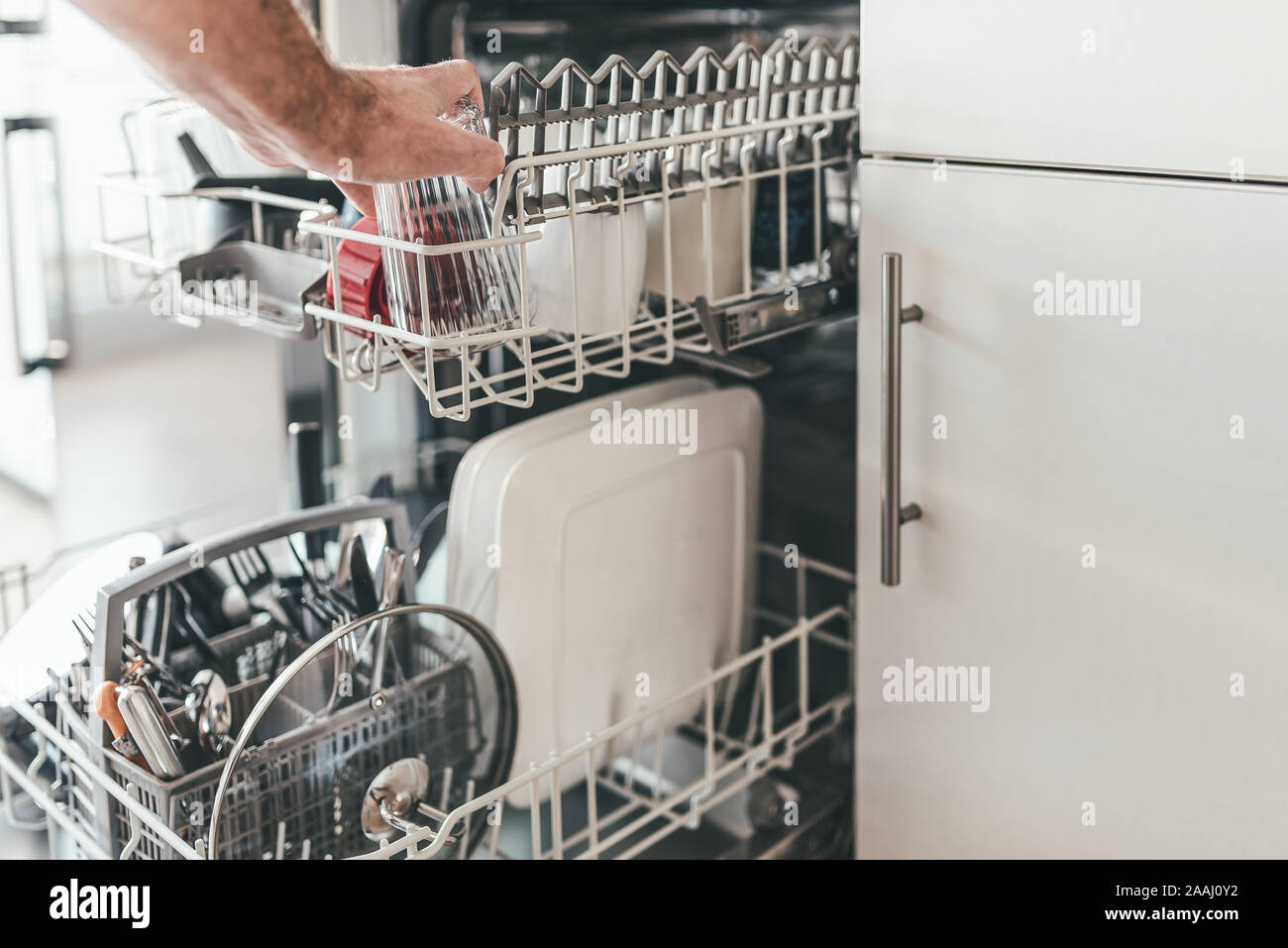 Close-up of man loading ou le vidage de lave-vaisselle dans la cuisine Banque D'Images