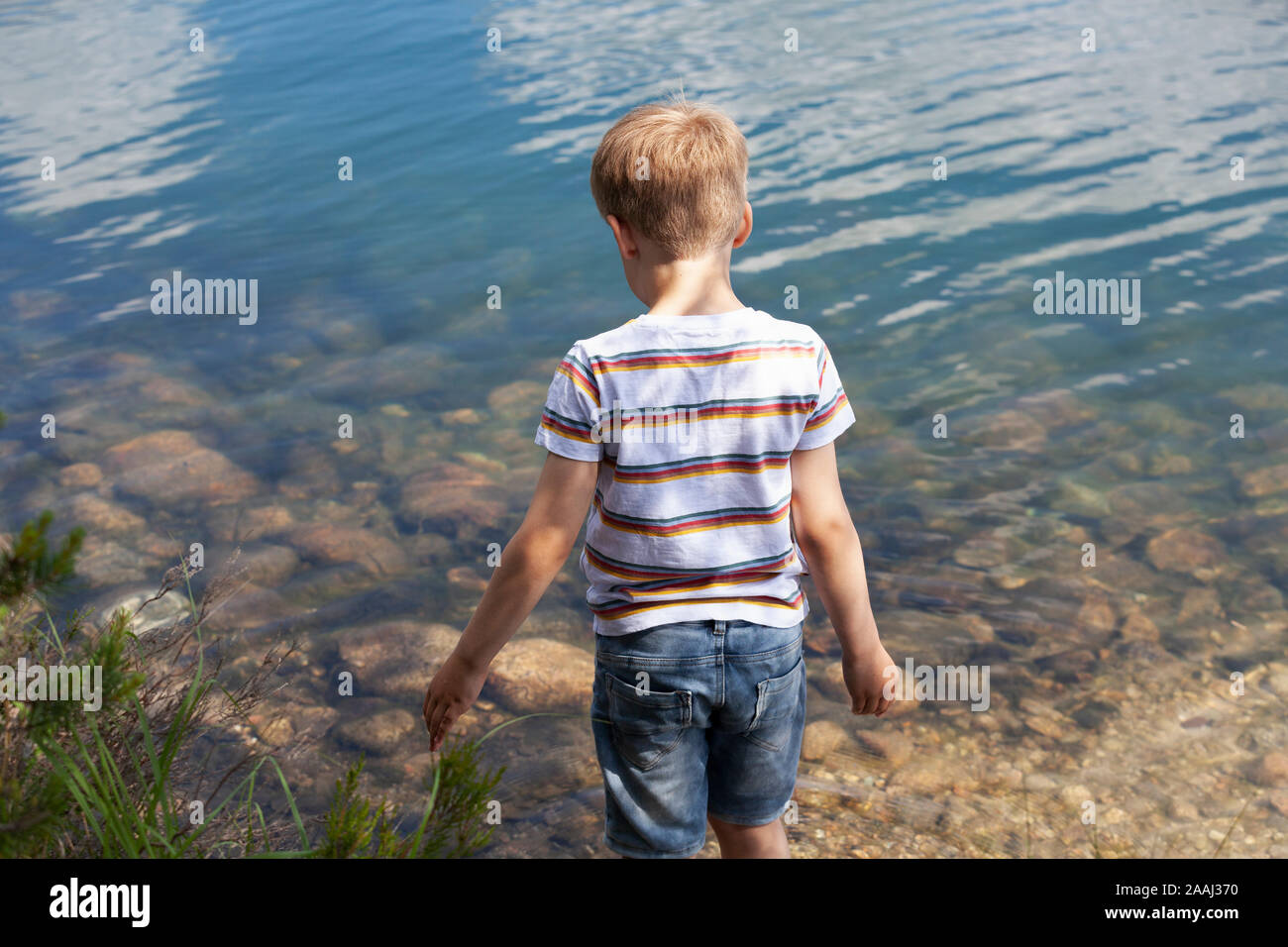 Garçon jouant près du lac Banque D'Images