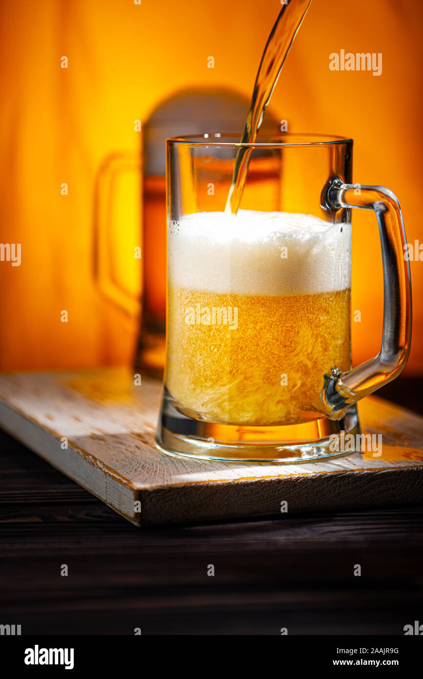 Verser la bière légère dans des tasses. Tasses en verre de bière light avec mousse blanche sur fond jaune Table et Woowen Banque D'Images