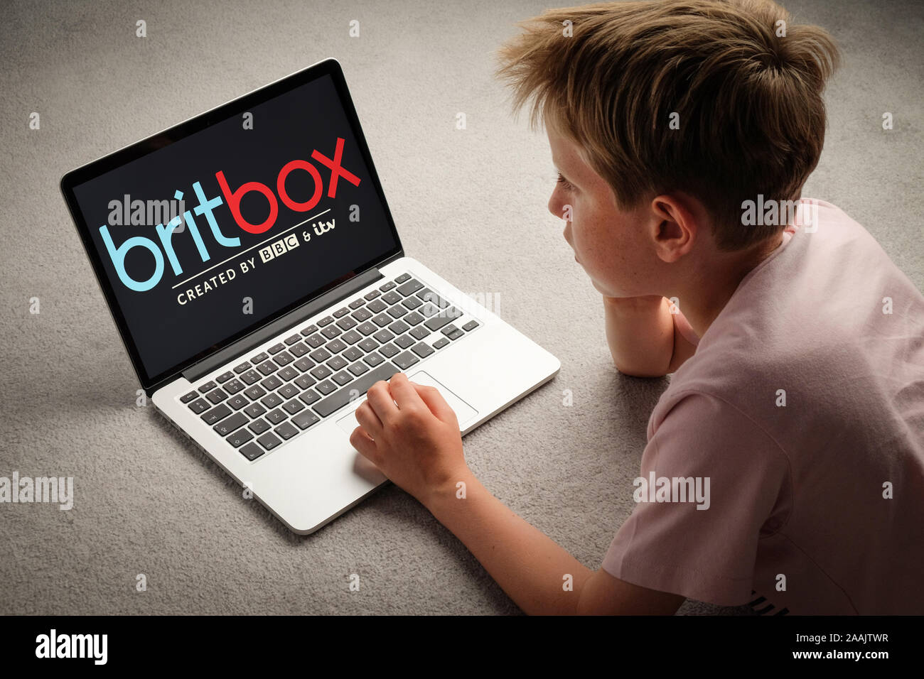 Un jeune garçon regardant britbox sur un ordinateur portable Banque D'Images
